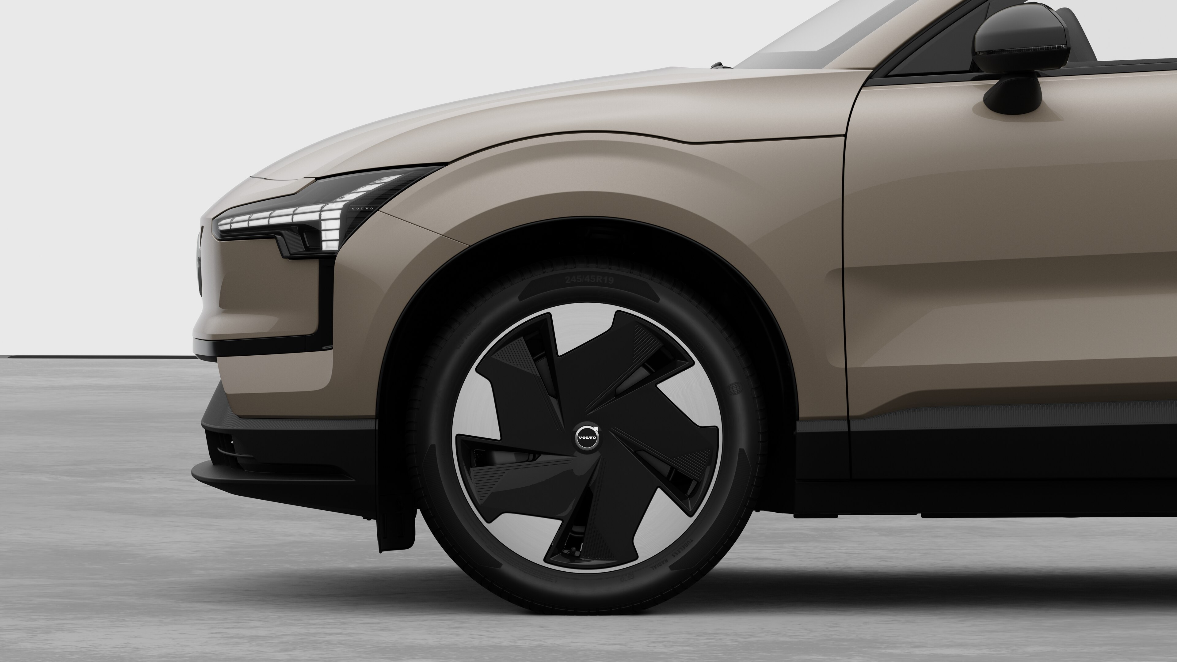 Volvo car exterior side view focusing on the front wheel and fender, set against a plain studio background.
