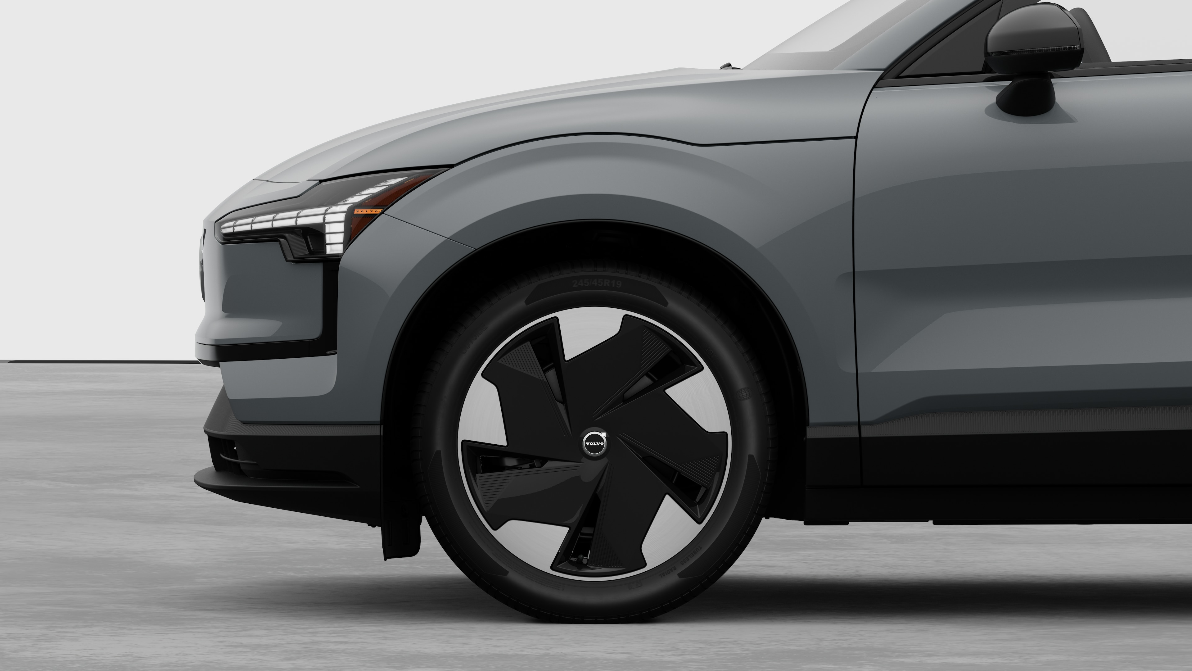 Vue latérale de l’extérieur d’une voiture Volvo, avec l’accent mis sur la roue avant et l’aile, sur un fond de studio uni.