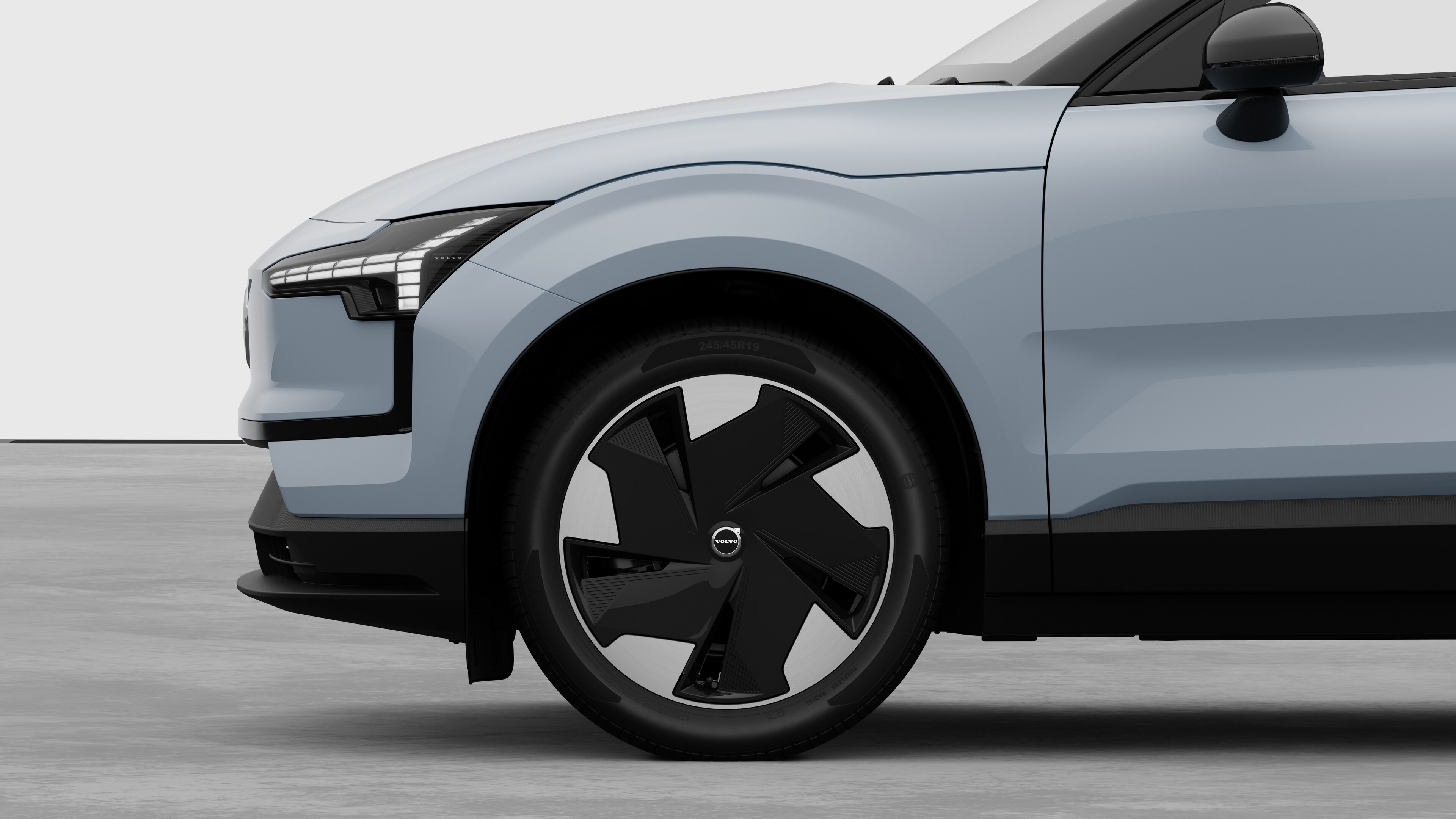 Volvo car exterior side view focusing on the front wheel and fender, set against a plain studio background.