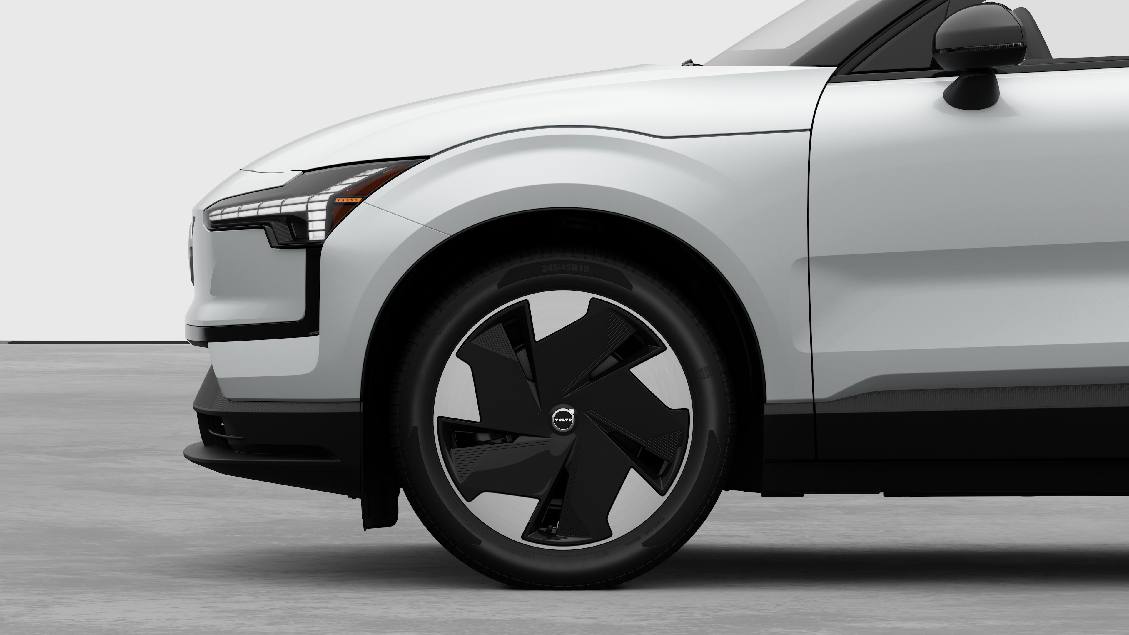 Volvo car exterior side view focusing on the front wheel and fender, set against a plain studio background.