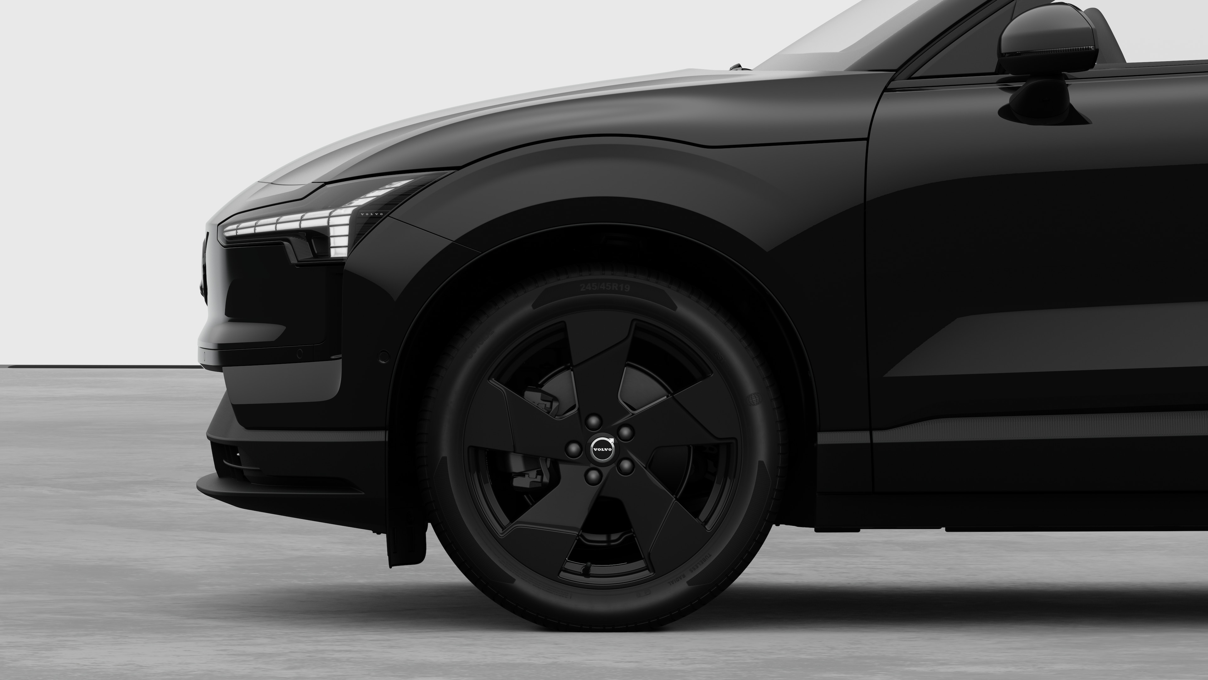 Volvo-bilens udvendige sidebillede med fokus på forhjulet og skærmen, sat op mod en almindelig studiebaggrund.