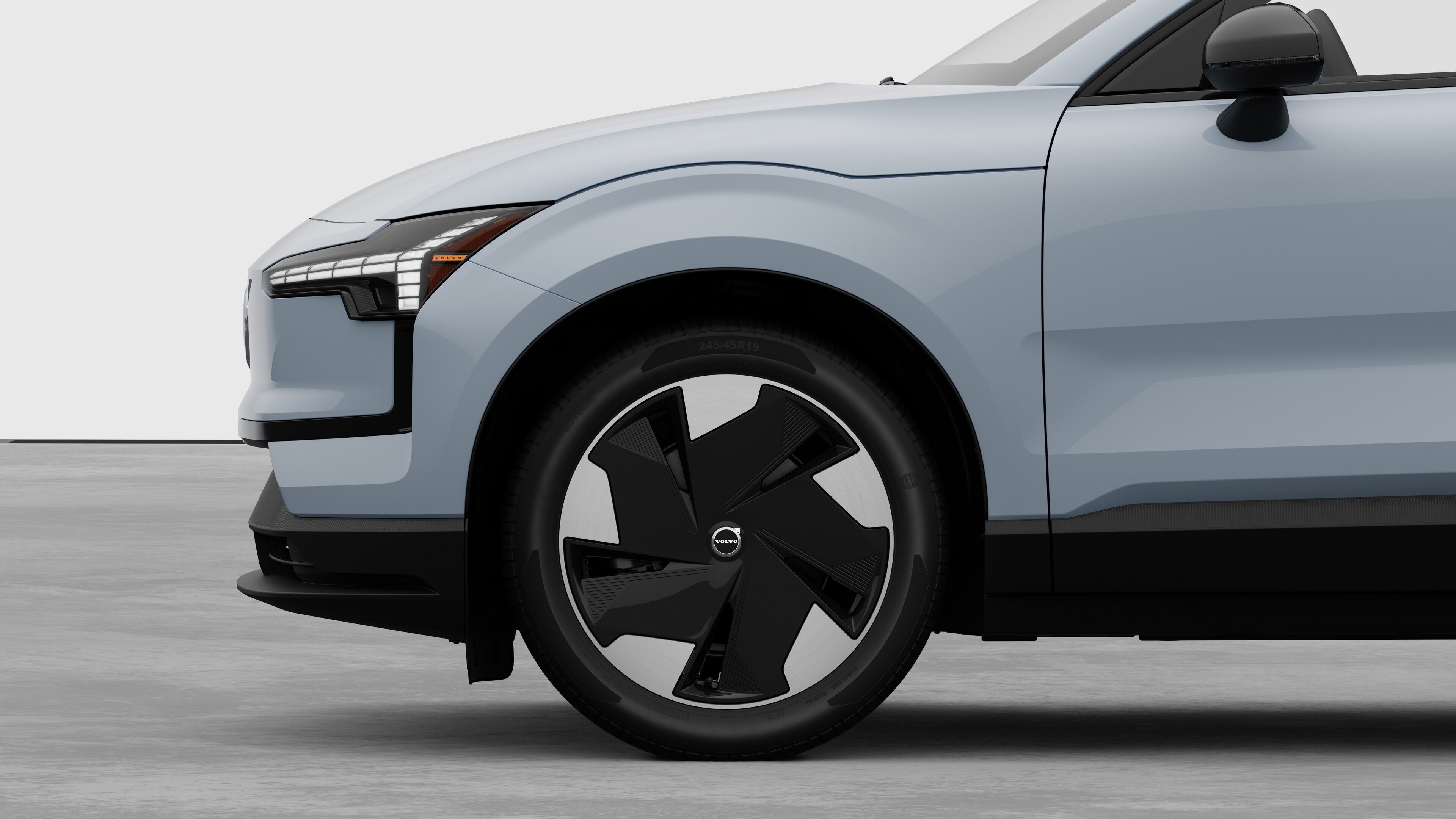 Vista lateral exterior del vehículo Volvo centrada en la rueda delantera y el guardabarros, sobre un fondo de estudio liso.