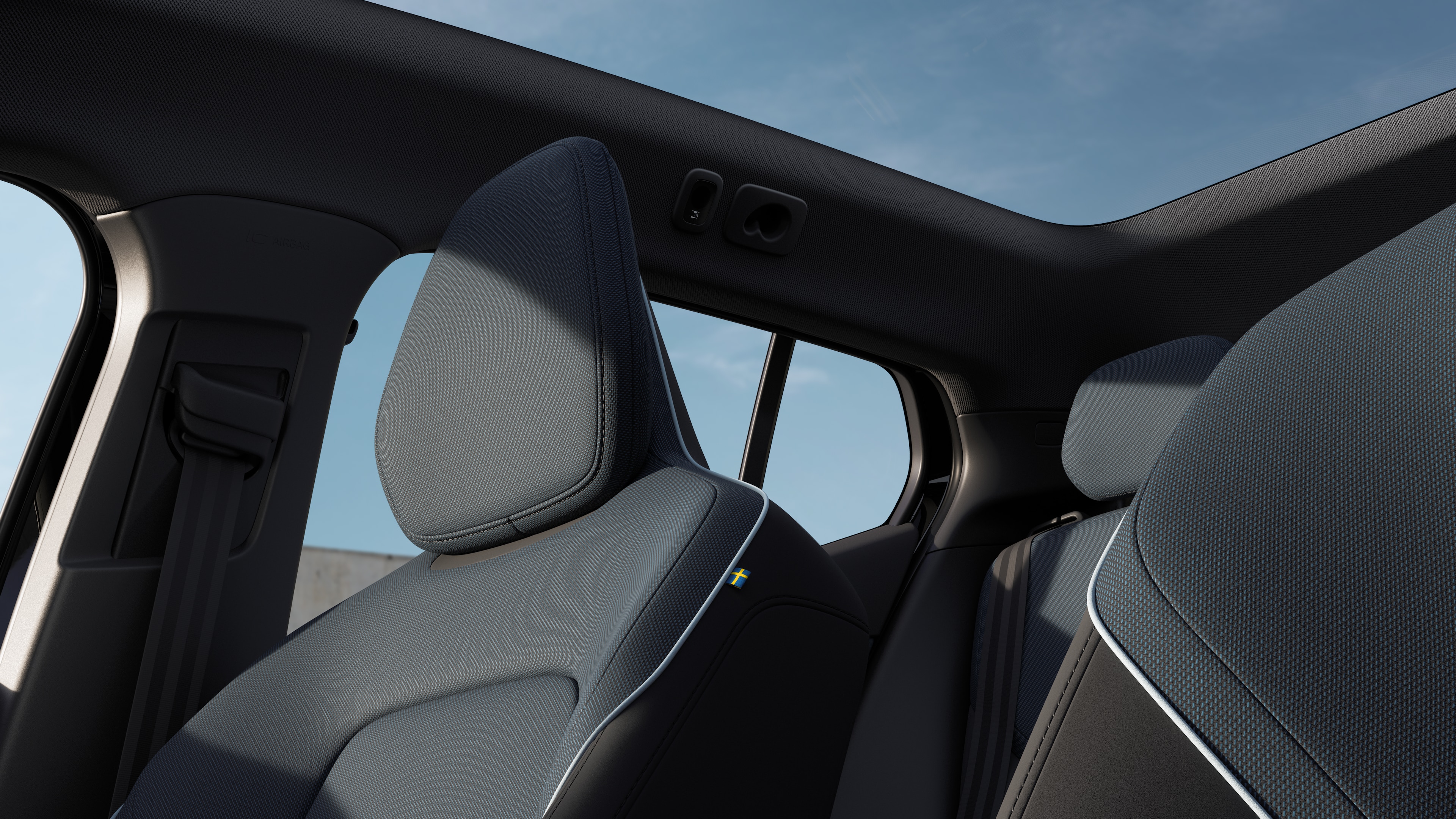 Het interieur van een Volvo met de passagiersstoelen voor- en achterin, het stuur, het dashboard en de middenconsole tegen een effen studioachtergrond.