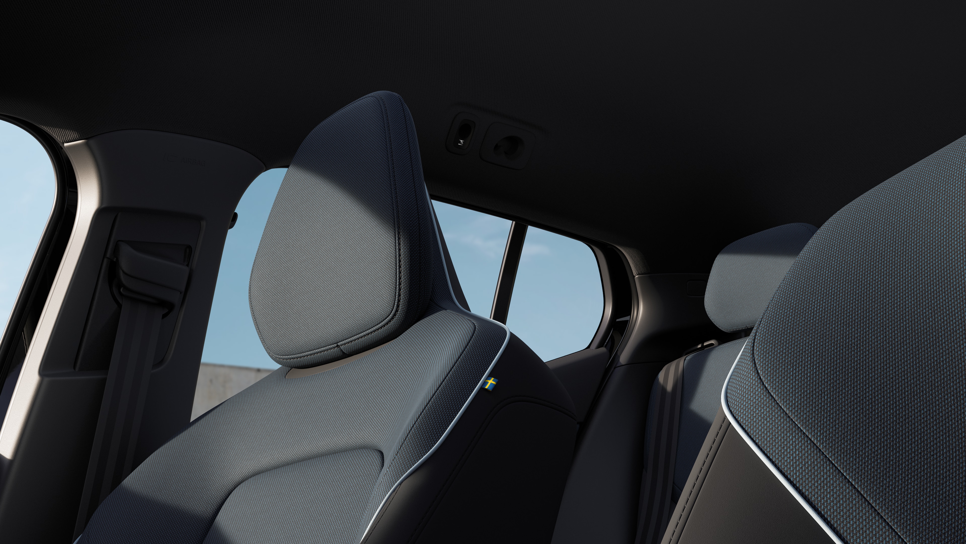 Het interieur van de Volvo met de passagiersstoelen voor- en achterin, het stuur, het dashboard en de middenconsole tegen een effen studioachtergrond.