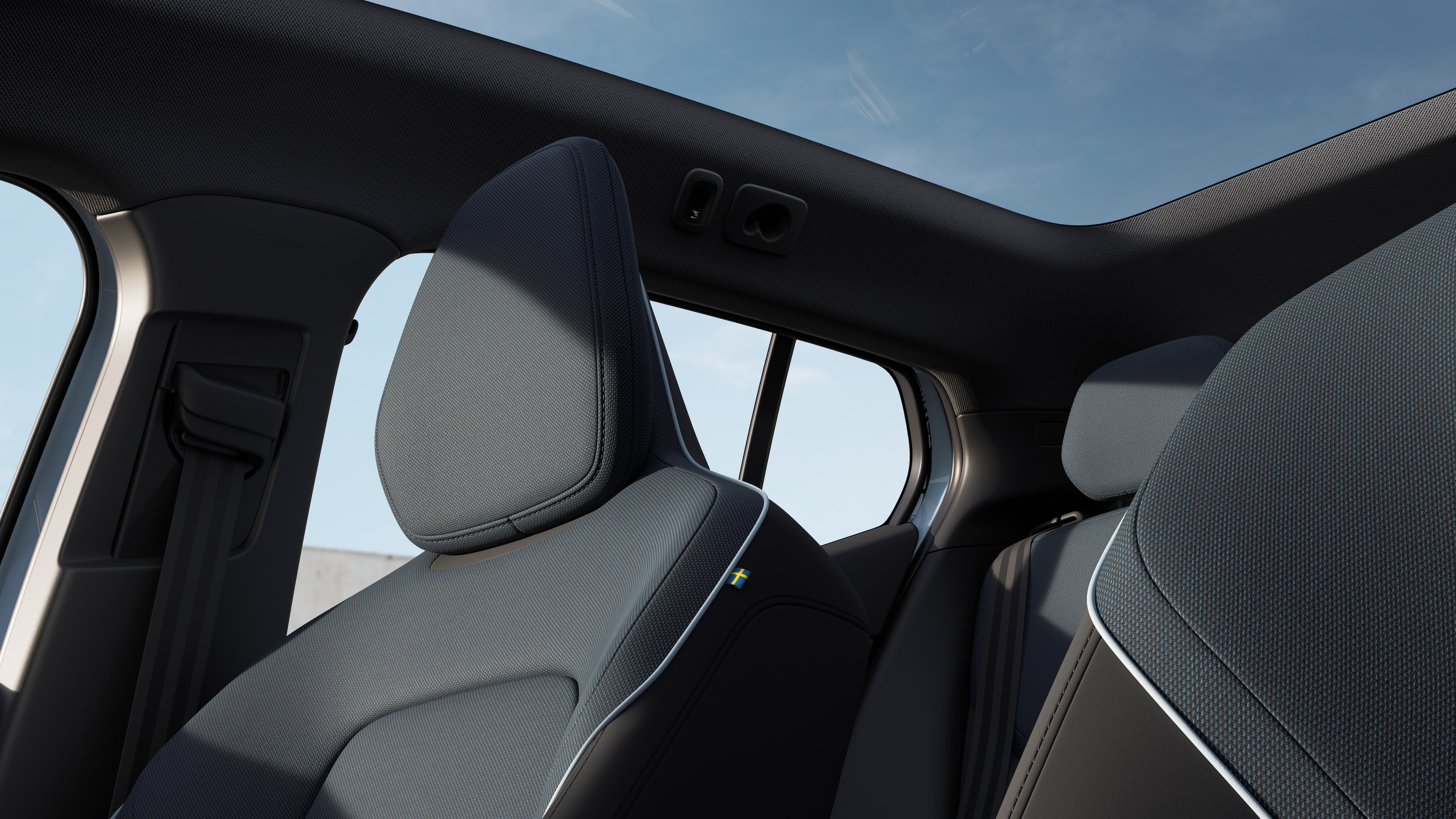 Het interieur van een Volvo met de passagiersstoelen voor- en achterin, het stuur, het dashboard en de middenconsole tegen een effen studioachtergrond.
