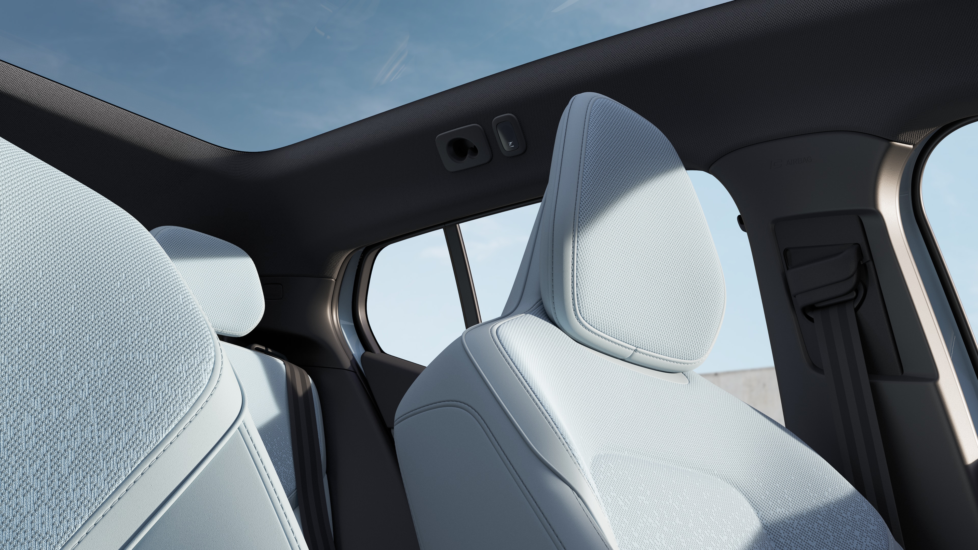 Volvo car interior showing front and rear passenger seats, steering wheel, dashboard, and center console against a plain studio background.