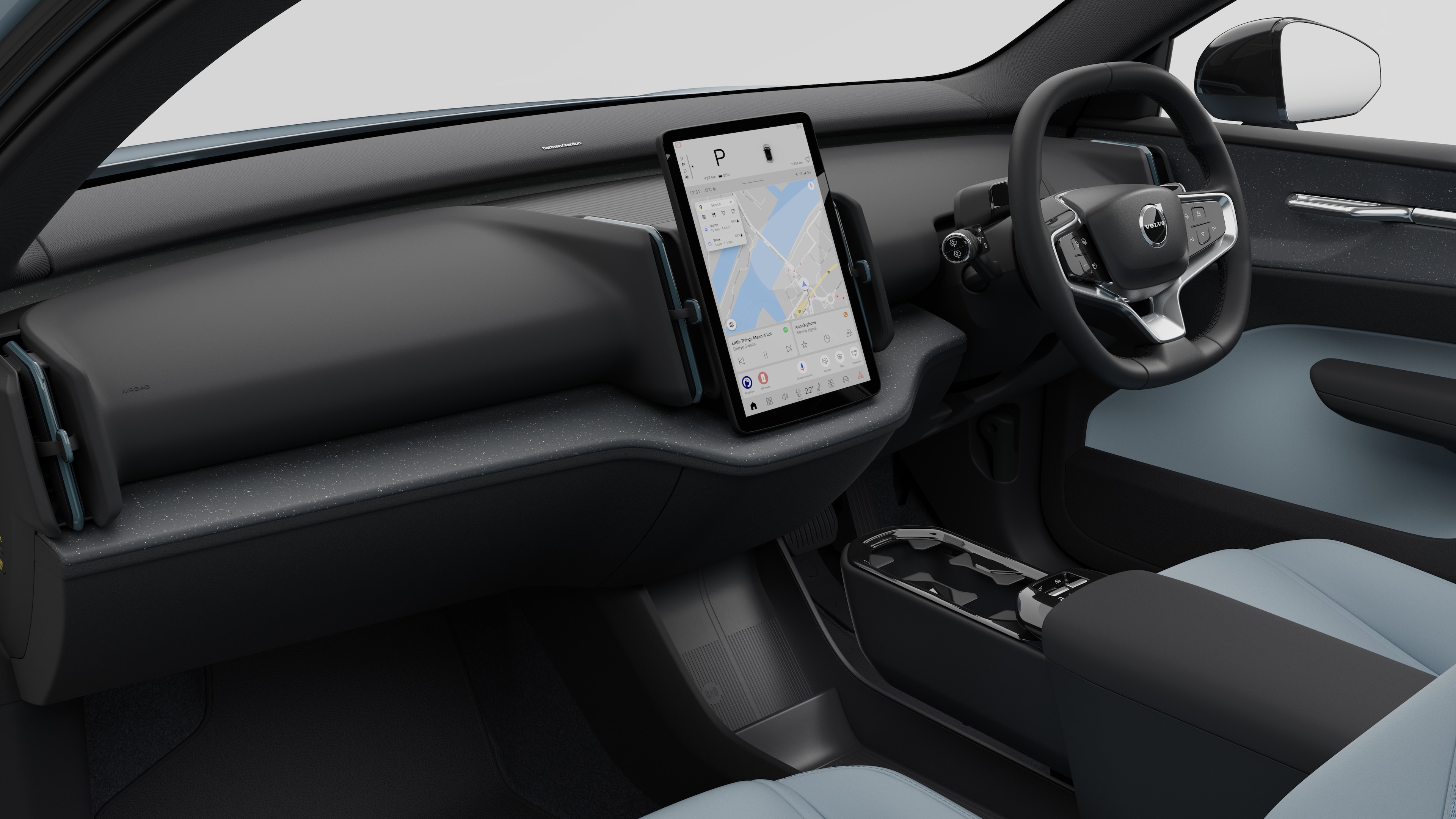 Interior view of a Volvo car showing the dashboard, steering wheel, center console, and digital display screen in a plain studio background.