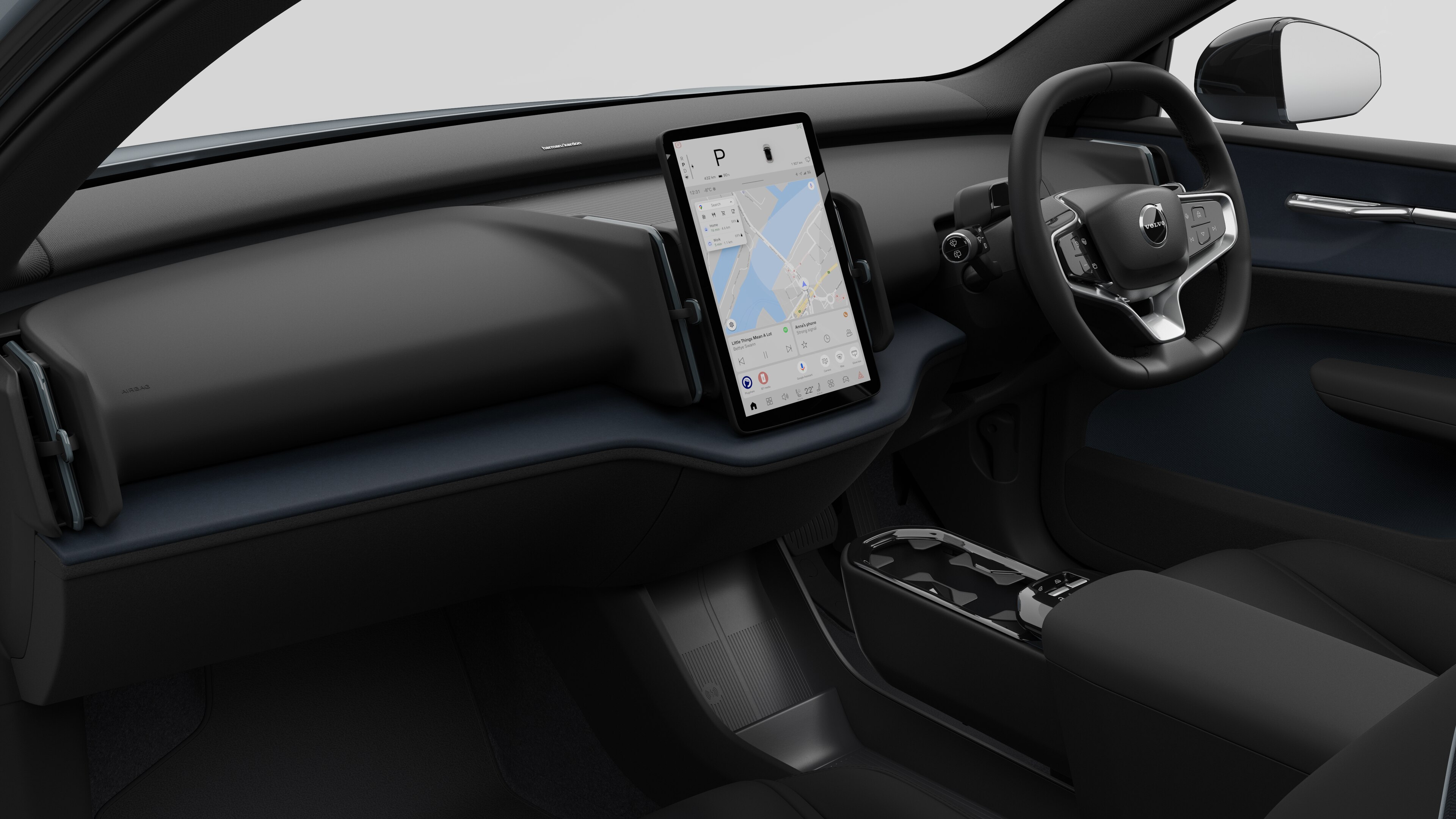 Interior view of a Volvo car showing the dashboard, steering wheel, center console, and digital display screen in a plain studio background.