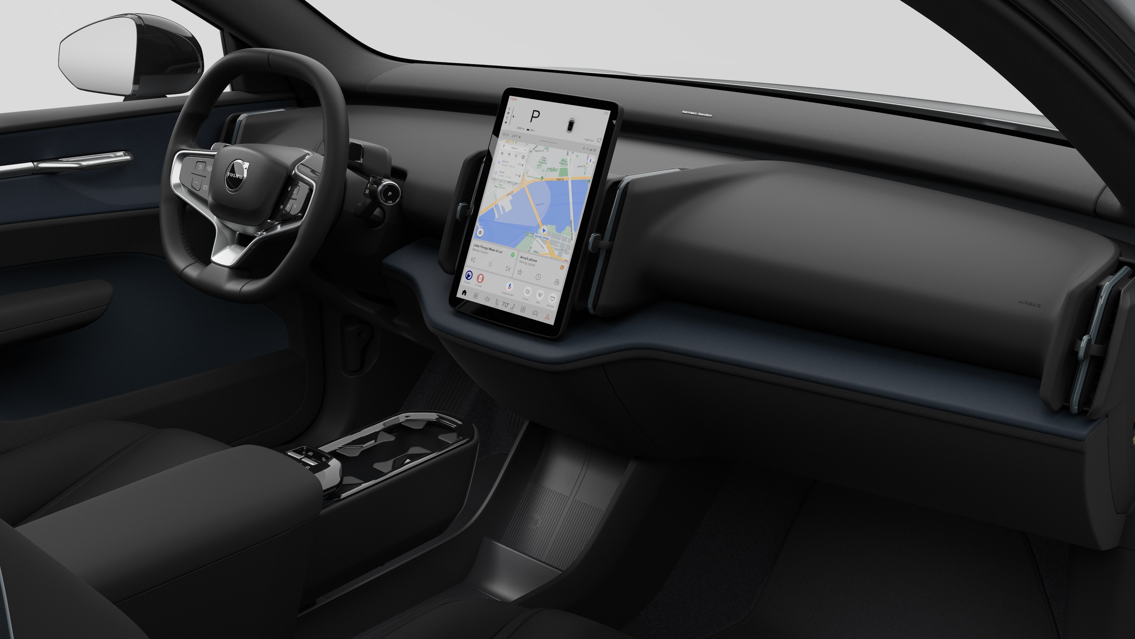 Interior view of a Volvo car showing the dashboard, steering wheel, center console, and digital display screen in a plain studio background.