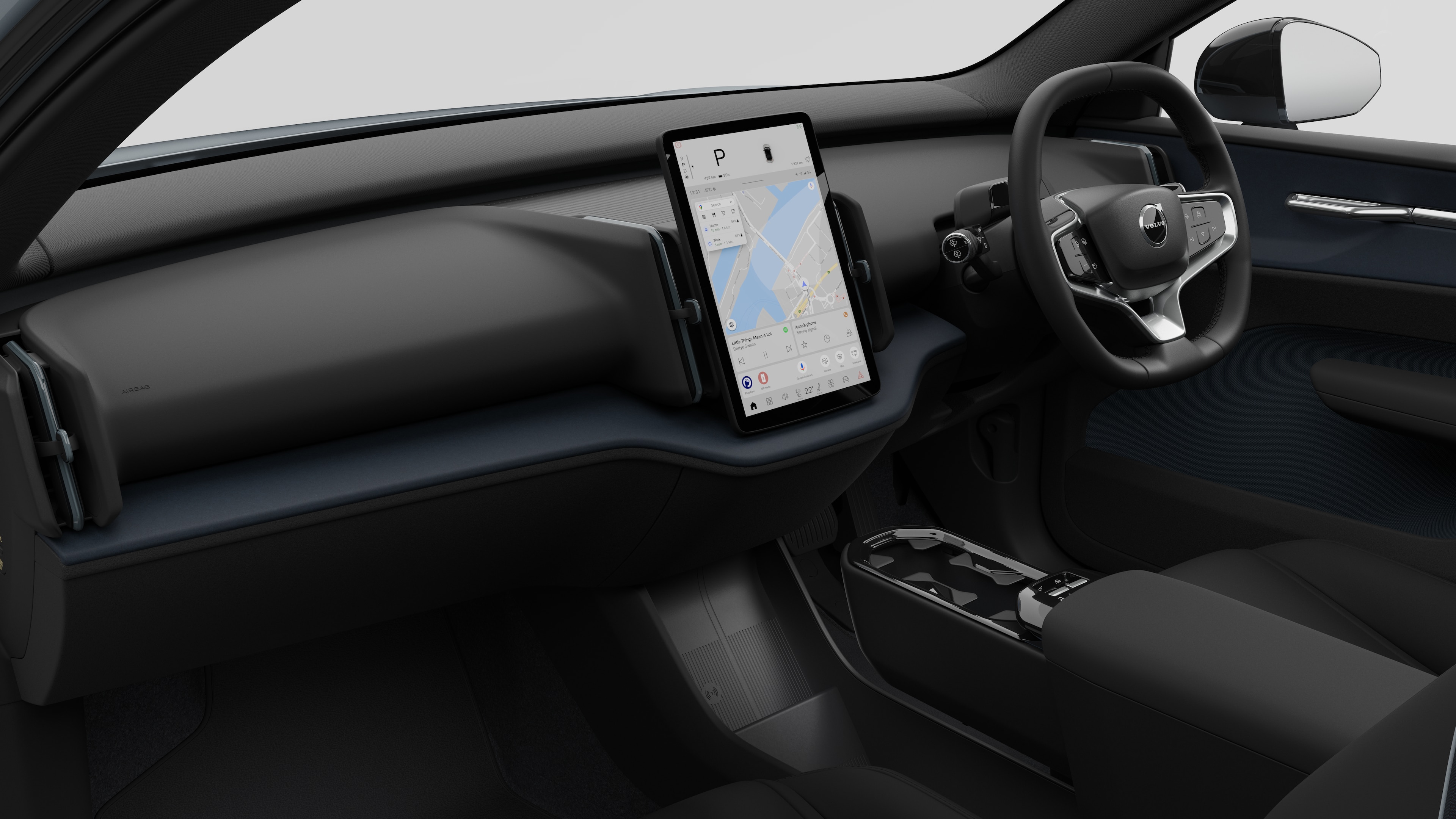 Interior view of a Volvo car showing the dashboard, steering wheel, center console, and digital display screen in a plain studio background.