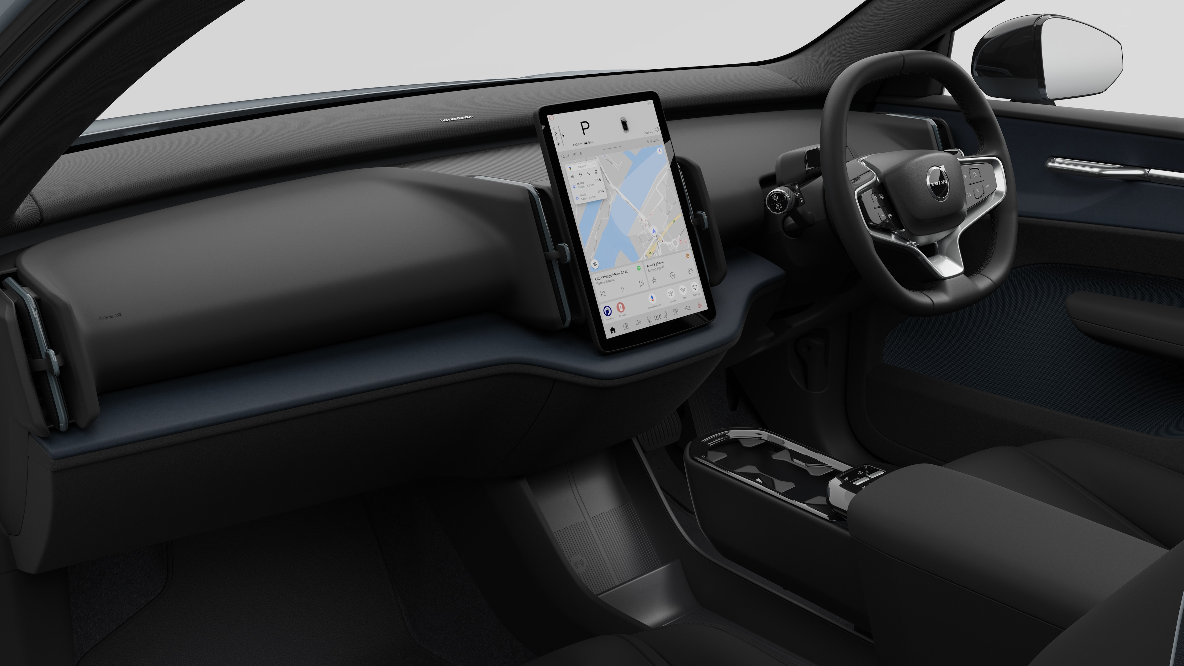 Interior view of a Volvo car showing the dashboard, steering wheel, center console, and digital display screen in a plain studio background.