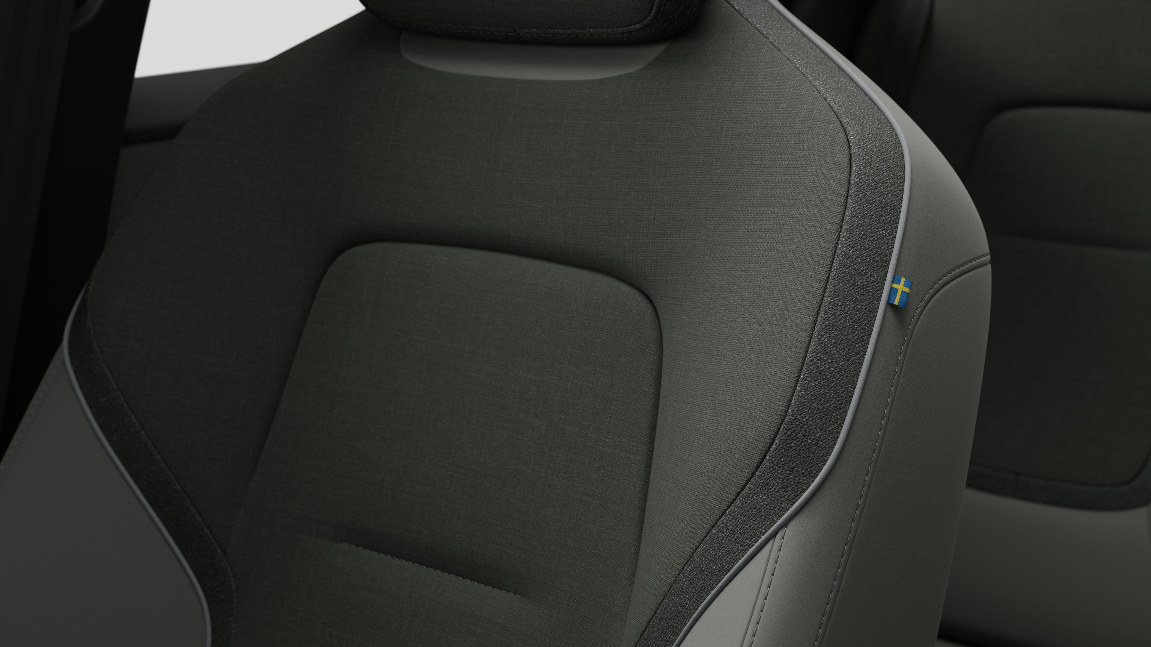 Grande plano dos detalhes do banco interior do automóvel Volvo a mostrar as costuras e uma pequena etiqueta da bandeira sueca.