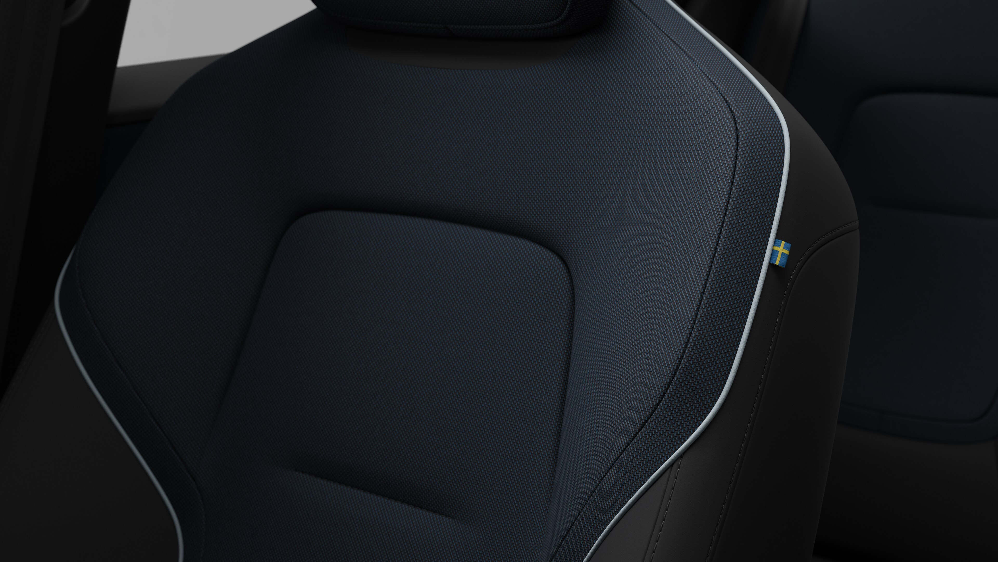 Close-up van een detail van de zetel in het interieur van een Volvo met stiksels en een klein Zweeds vlaglabel.