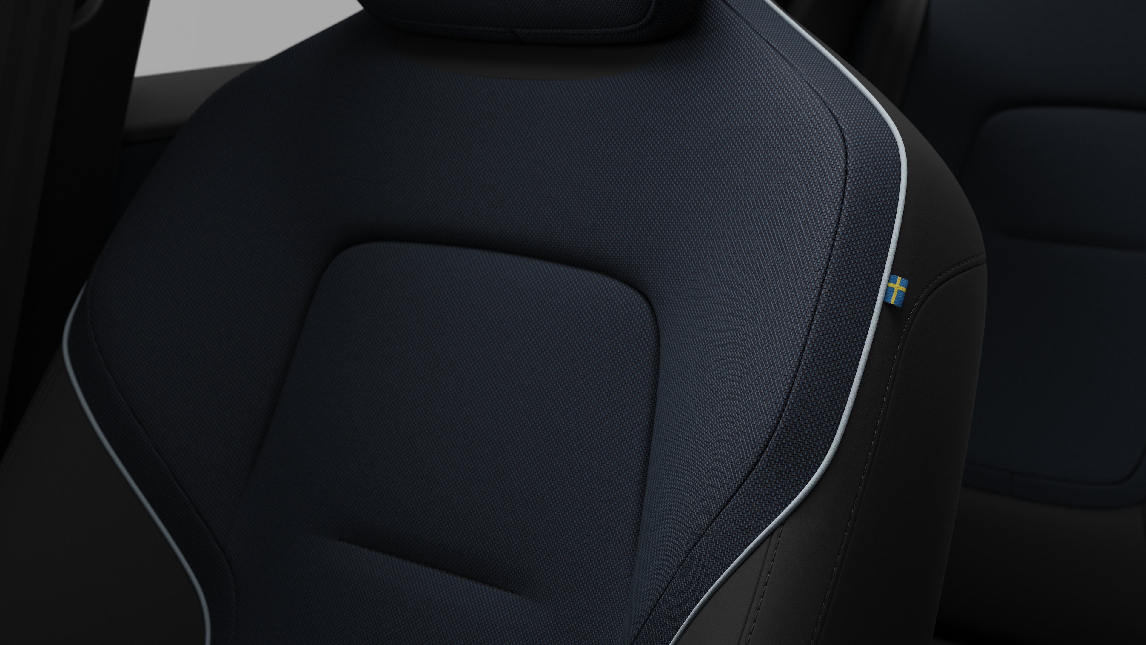 Close-up van een detail van de zetel in het interieur van een Volvo met stiksels en een klein Zweeds vlaglabel.