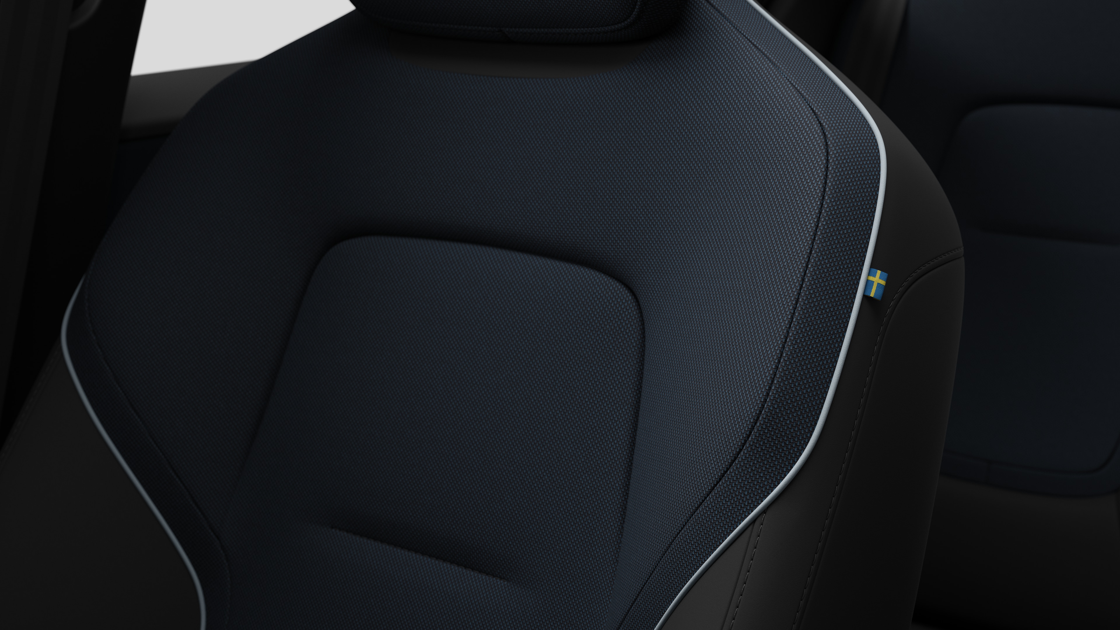 Primer plano del detalle del asiento interior del vehículo Volvo que muestra costuras y una pequeña etiqueta con la bandera sueca.