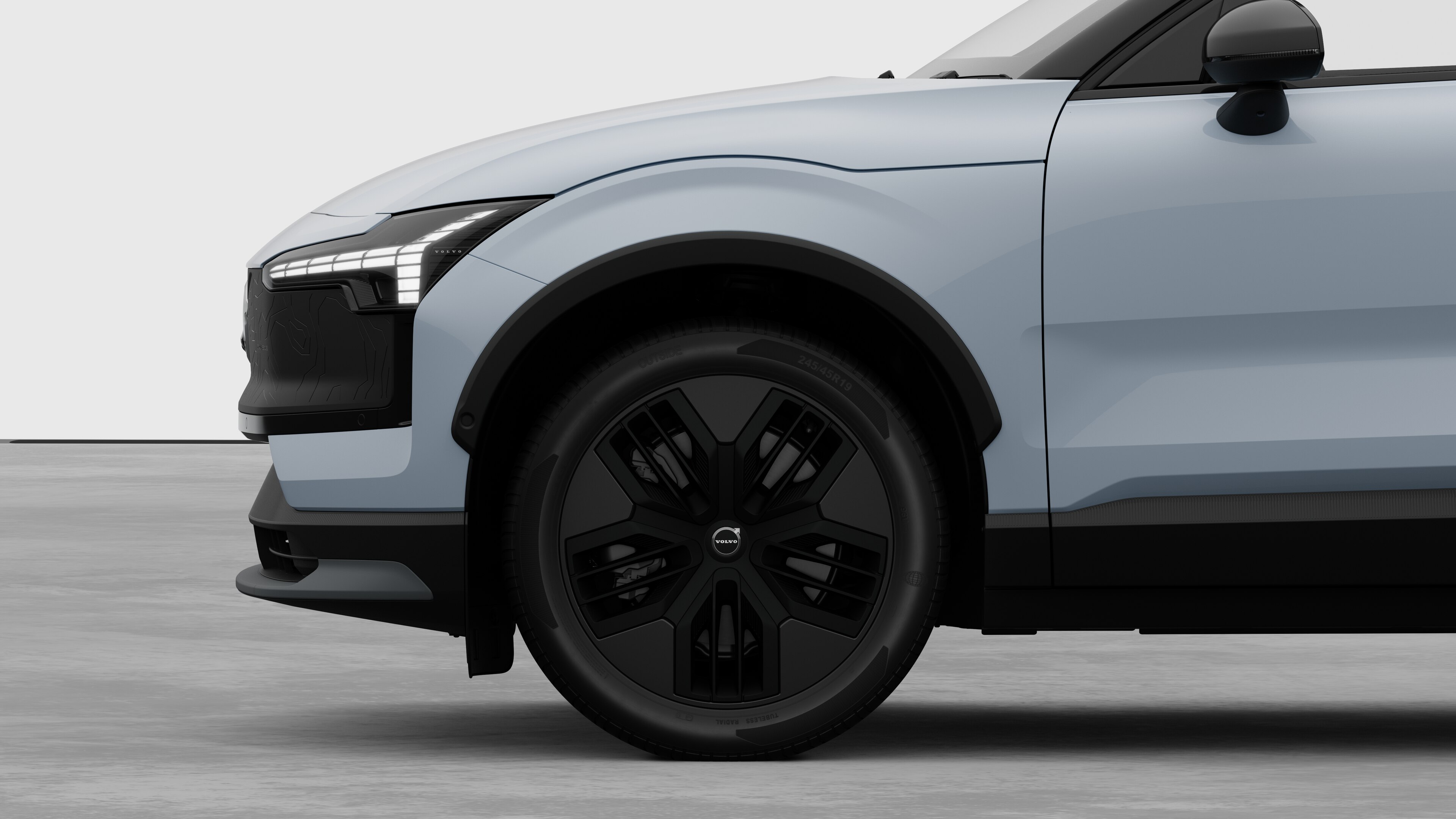 Volvo car exterior side view focusing on the front wheel and fender, set against a plain studio background.