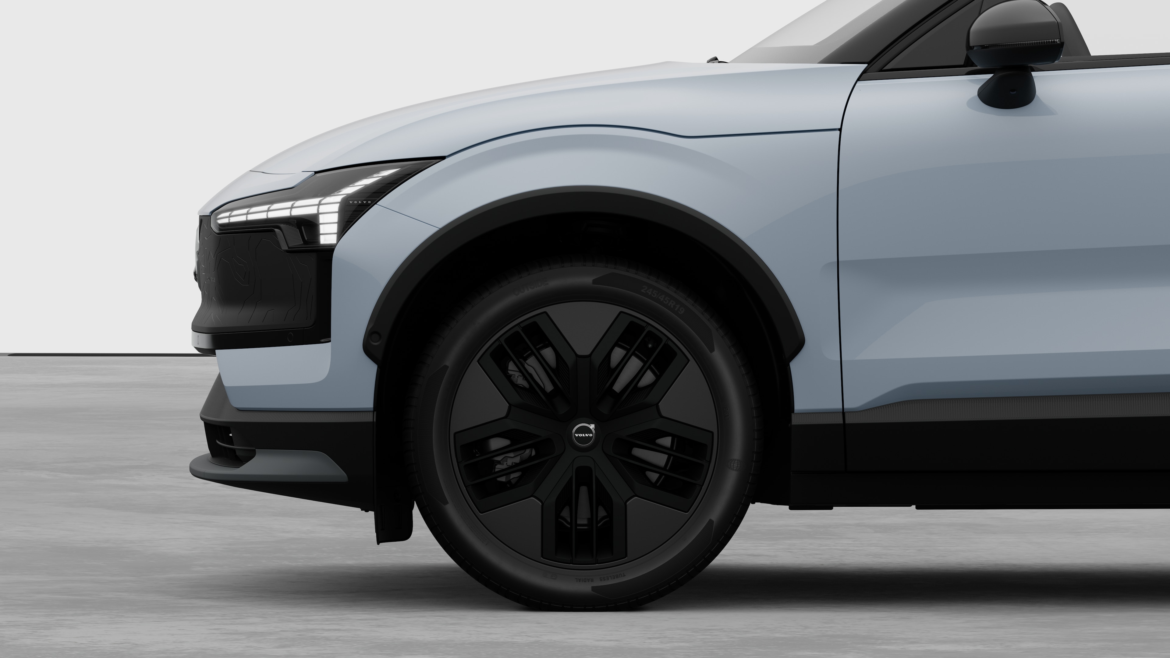 Vue latérale de l’extérieur d’une Volvo se concentrant sur la roue avant et l’aile, sur un fond de studio uni.