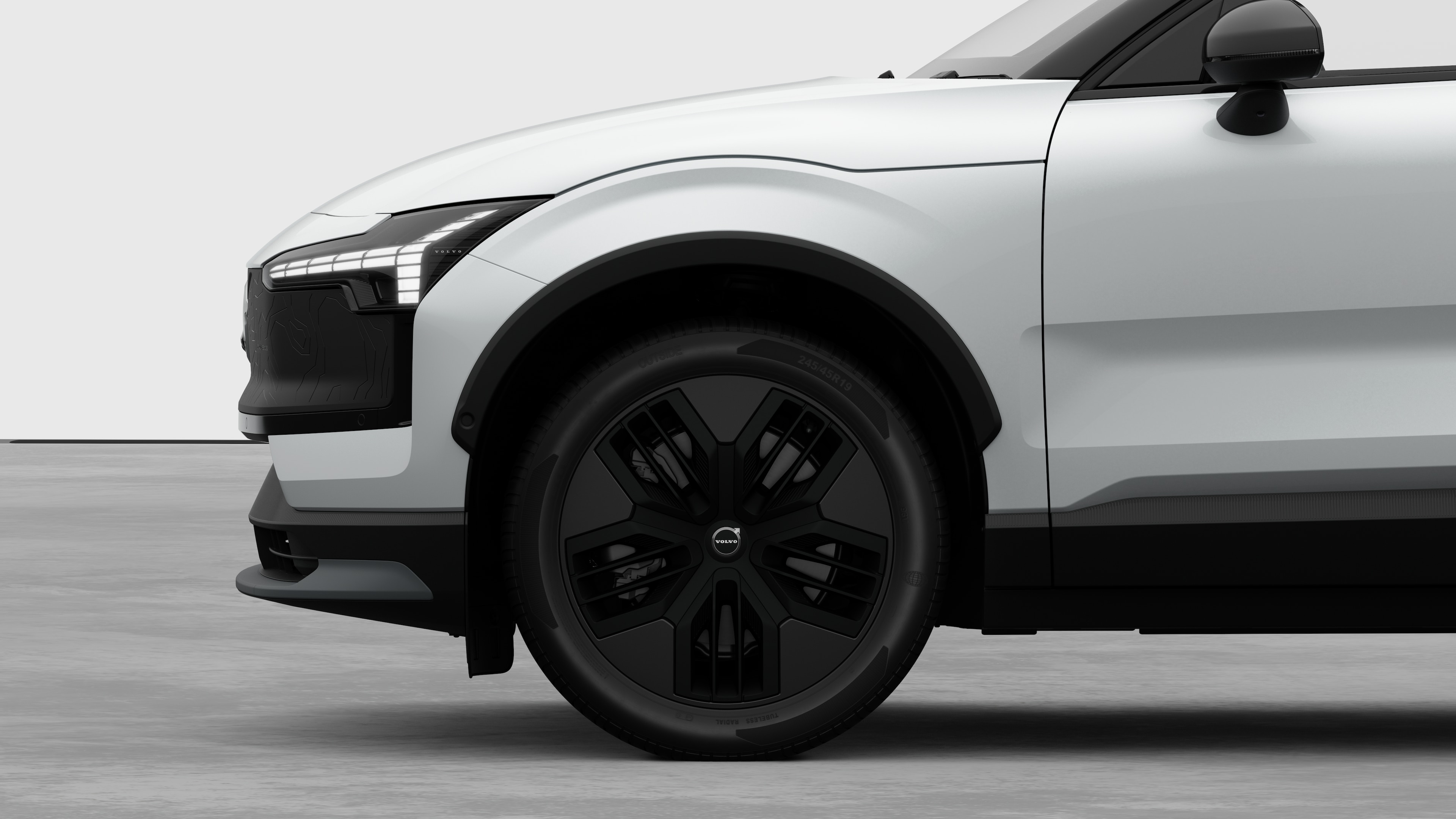 無地のスタジオを背景に、フロントホイールとフェンダーに焦点を合わせたボルボ車のエクステリアサイドビュー。