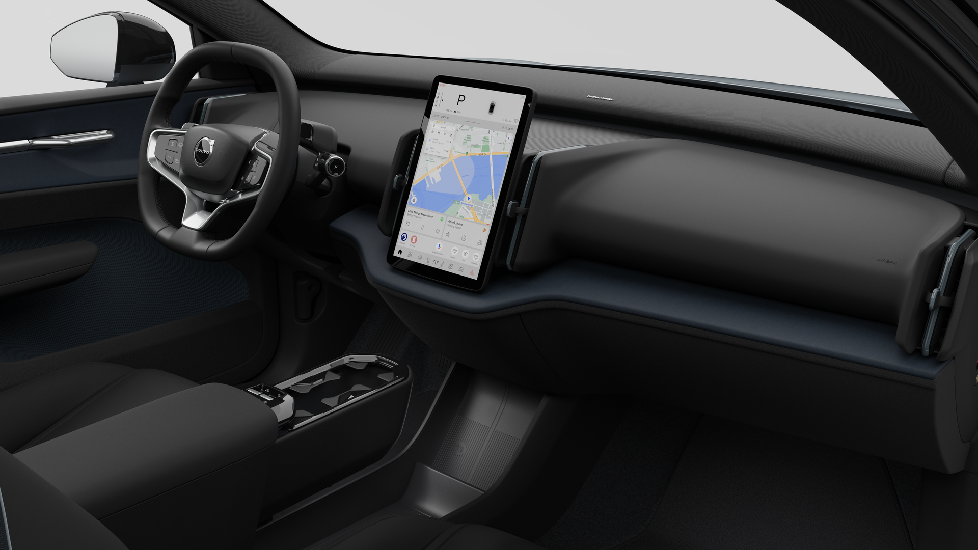 Interior view of a Volvo car showing the dashboard, steering wheel, center console, and digital display screen in a plain studio background.