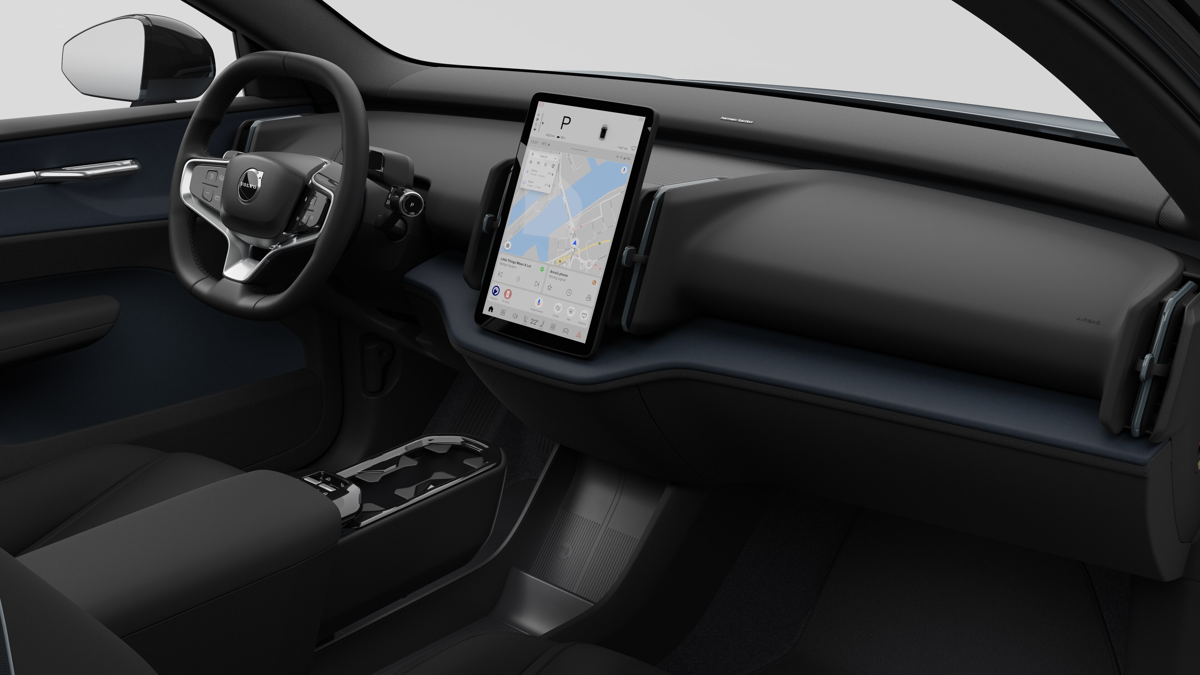 Interior view of a Volvo car showing the dashboard, steering wheel, center console, and digital display screen in a plain studio background.