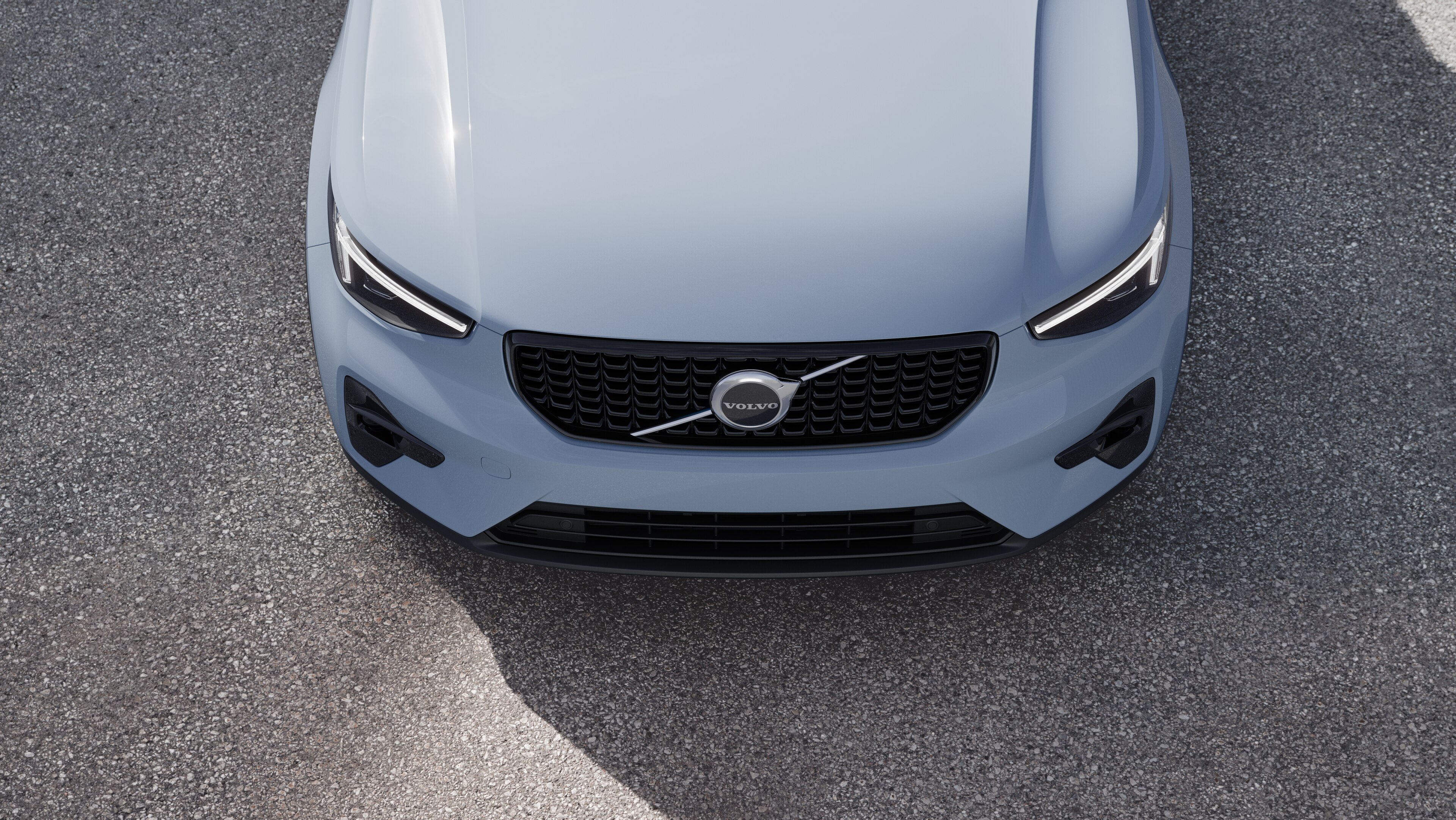 منظر خارجي لسيارة فولفو من ثلاثة أرباع سيارة فولفو على خلفية شارع حضري، يظهر جانبا واحدا وسقفا وجزءا من المقدمة.