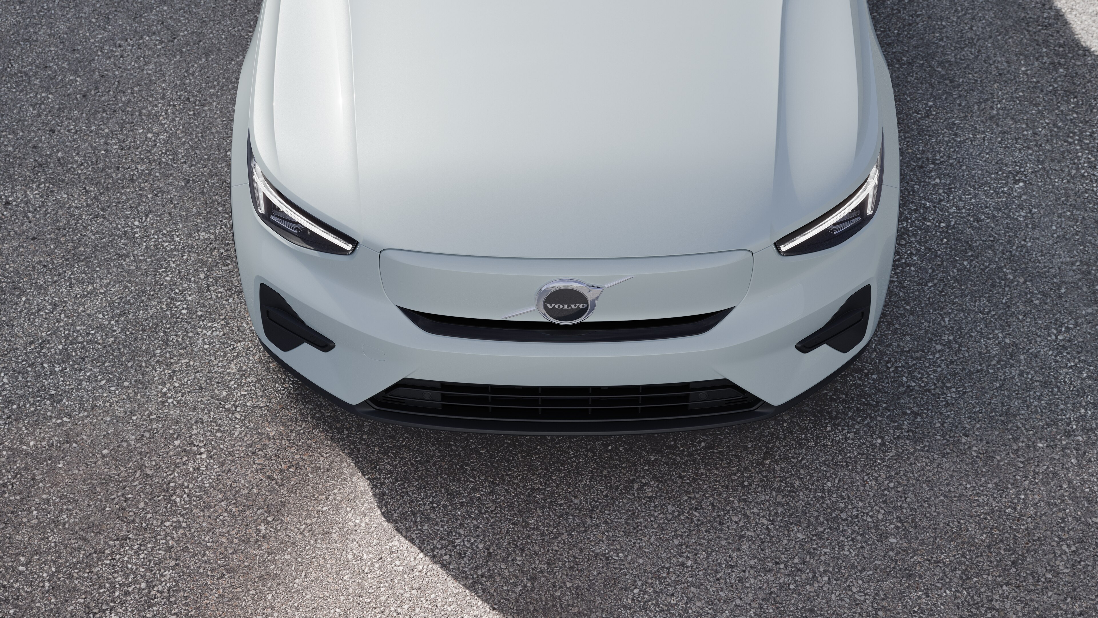 L’extérieur d’une voiture Volvo vue de trois quarts sur un arrière-plan de rue urbaine, montrant un côté, le toit et une partie de l’avant.