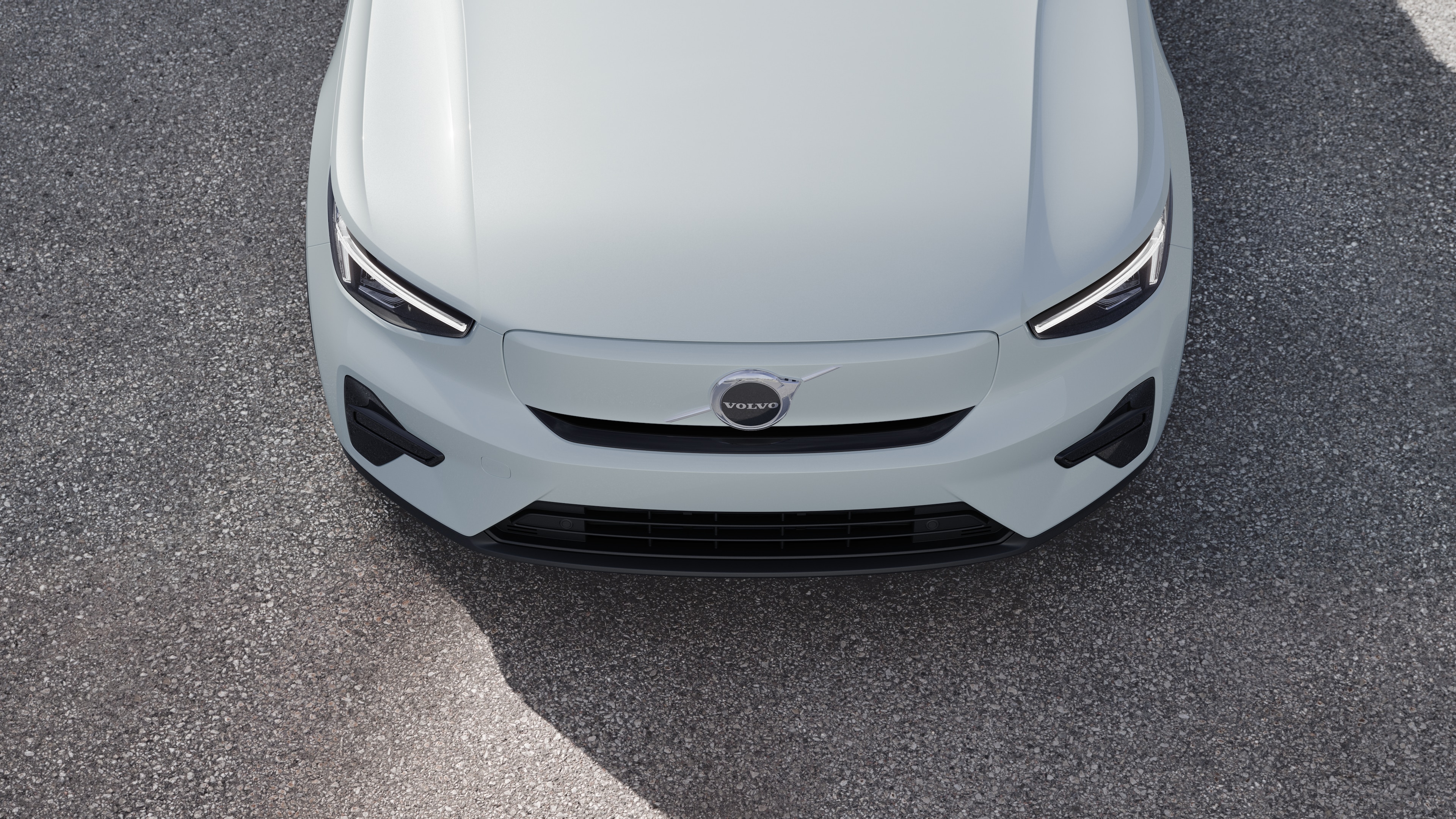 Volvo-bíll að utan í þriggja fjórðu hluta götubakgrunns í þéttbýli sem sýnir aðra hliðina, þakið og hluta framhliðarinnar.