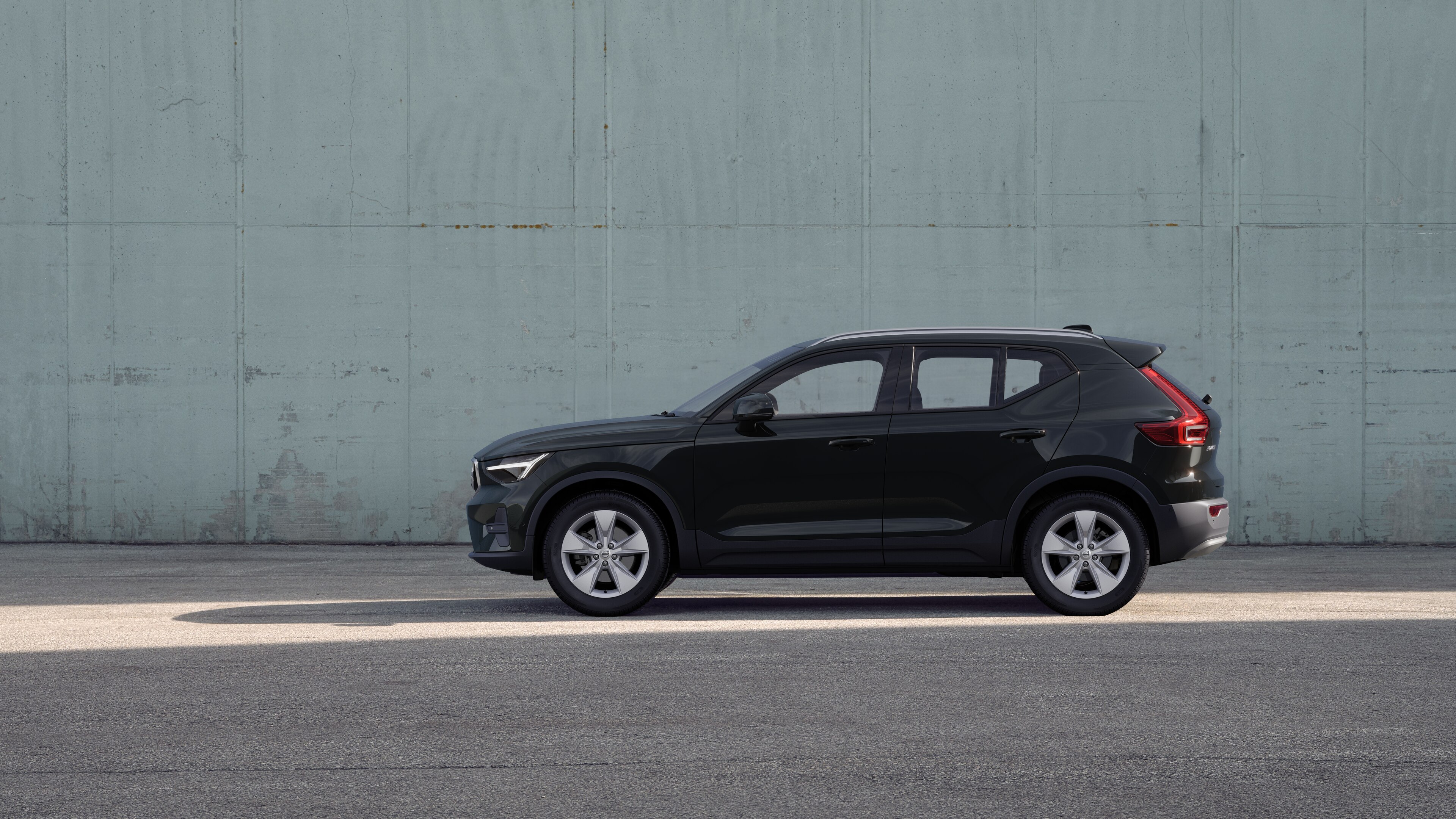 コンクリートの壁を背景に駐車したボルボ車のサイドビュー。