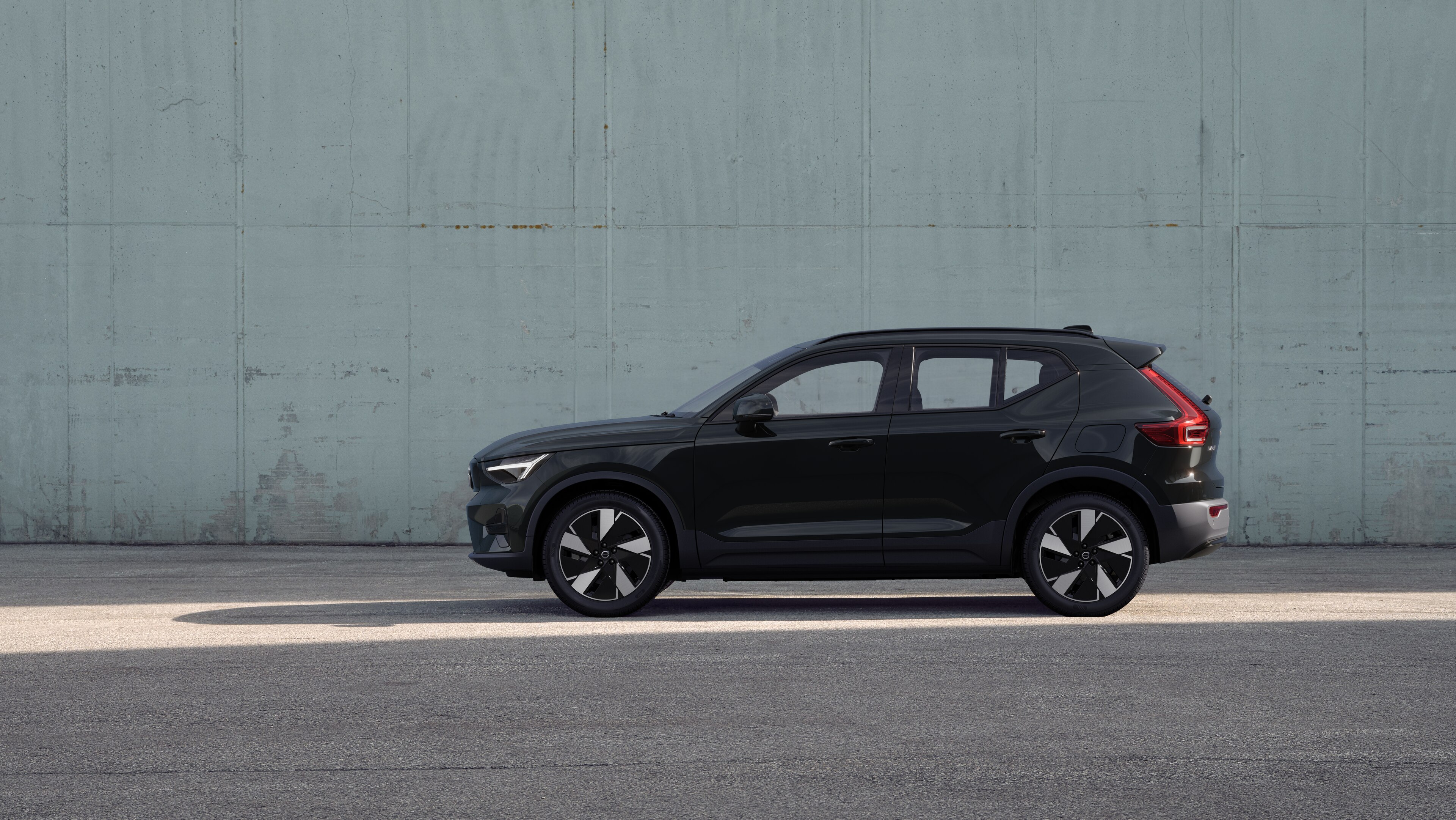 Volvo car, side view, parked against a plain concrete wall background.