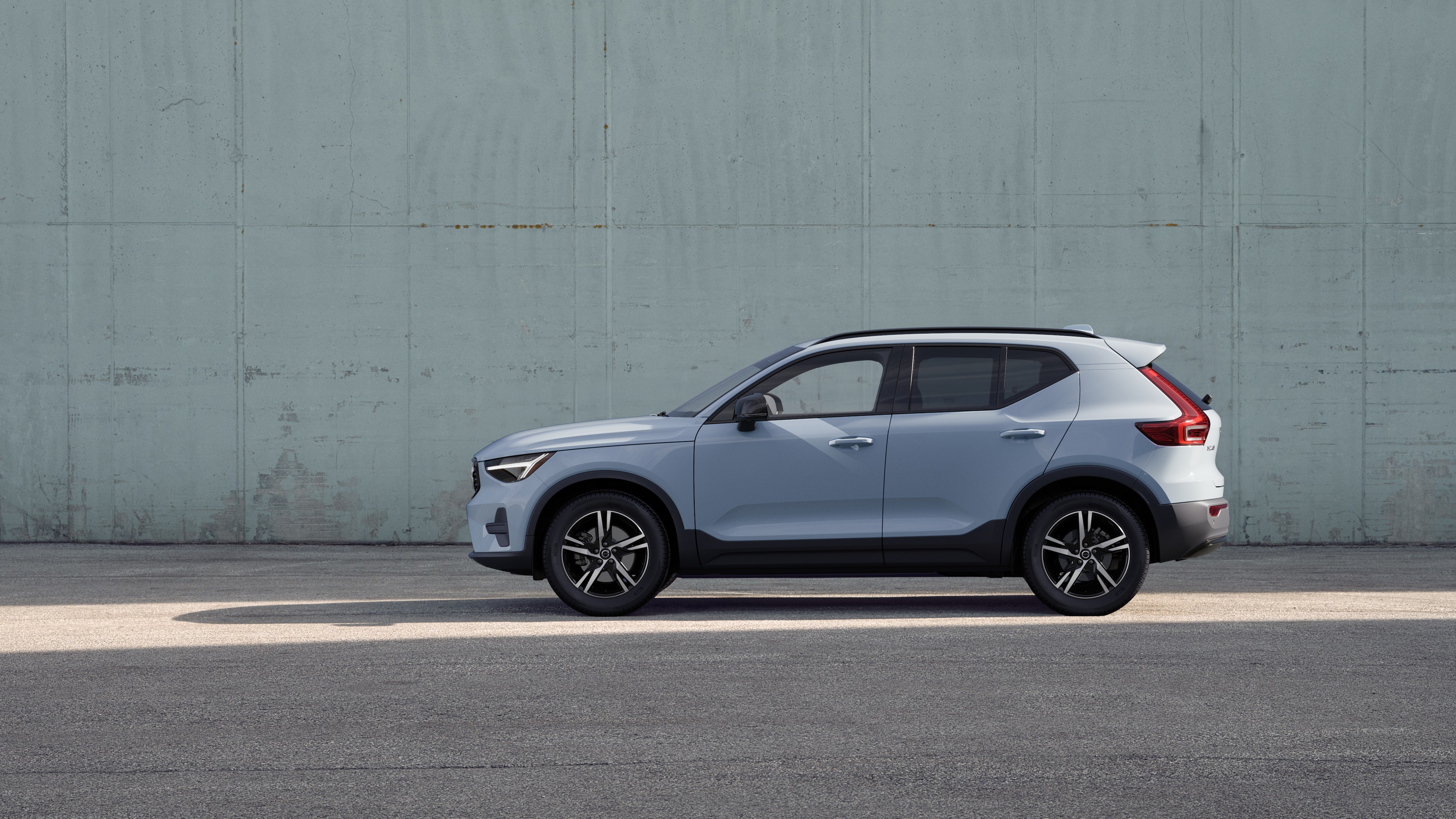 Volvo car, side view, parked against a plain concrete wall background.