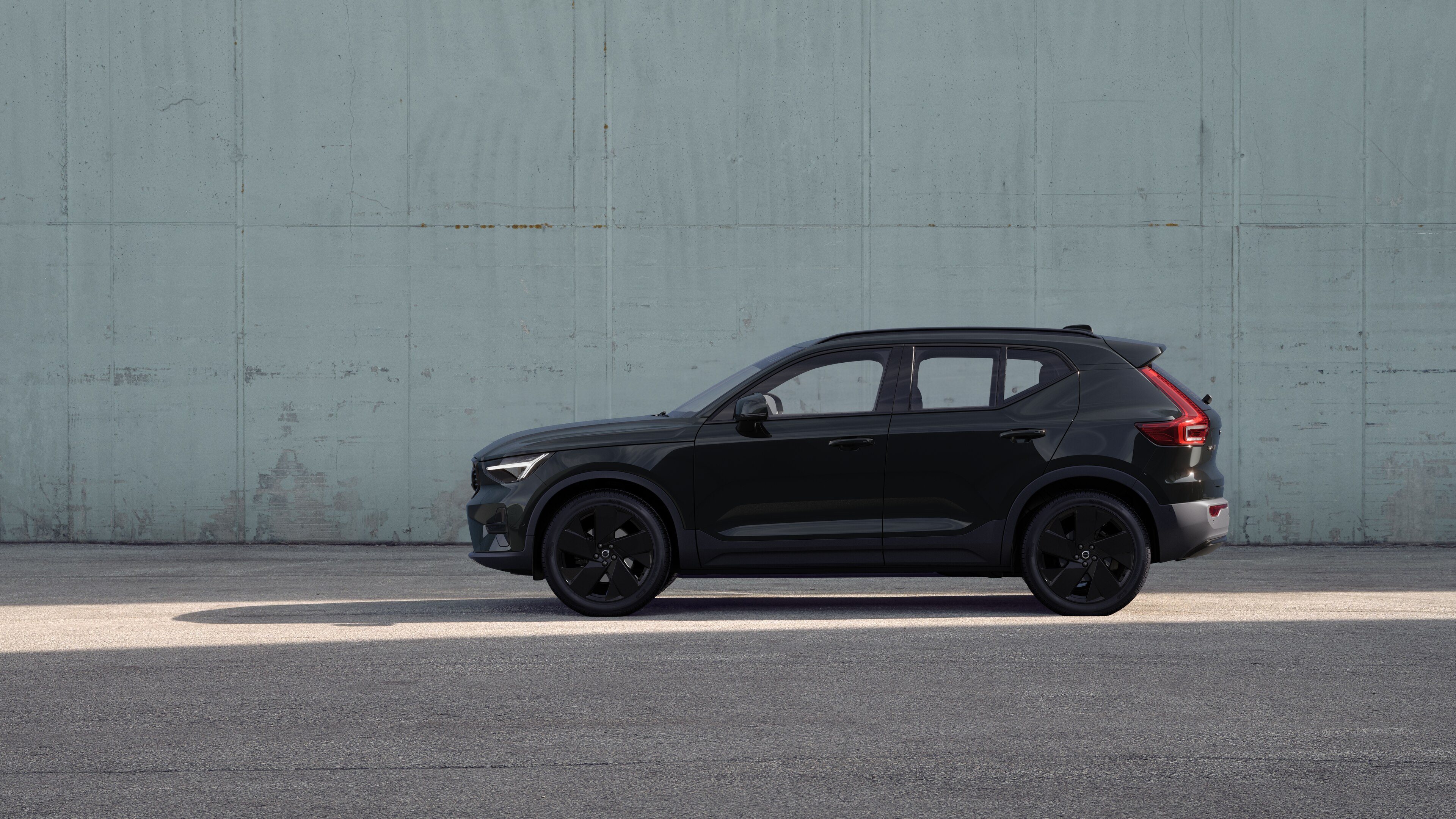 Un'auto Volvo, vista laterale, parcheggiata sullo sfondo di un muro di cemento.