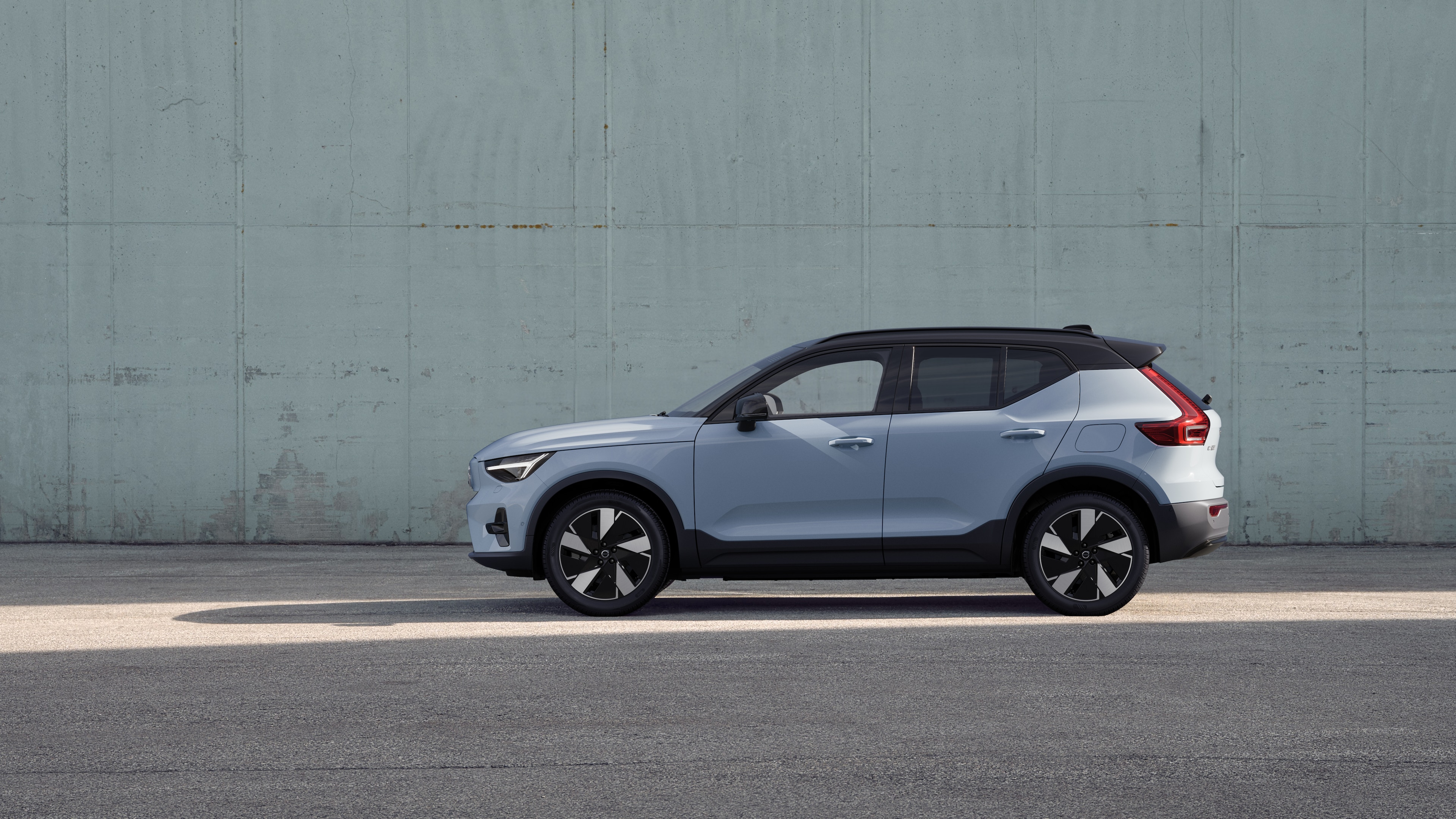 מכונית וולוו, מבט מהצד, חונה על רקע קיר בטון פשוט.