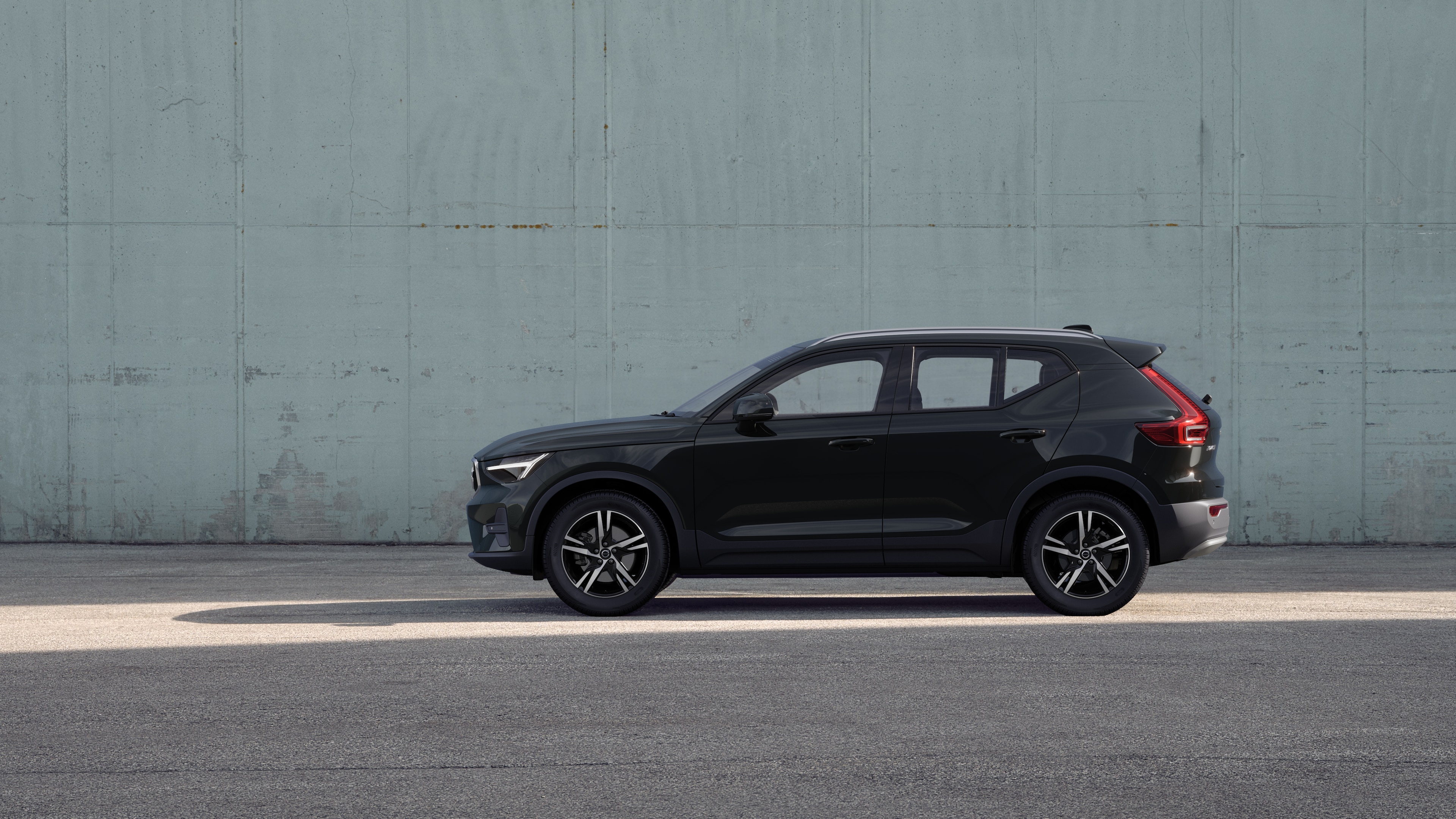 Volvo car, side view, parked against a plain concrete wall background.