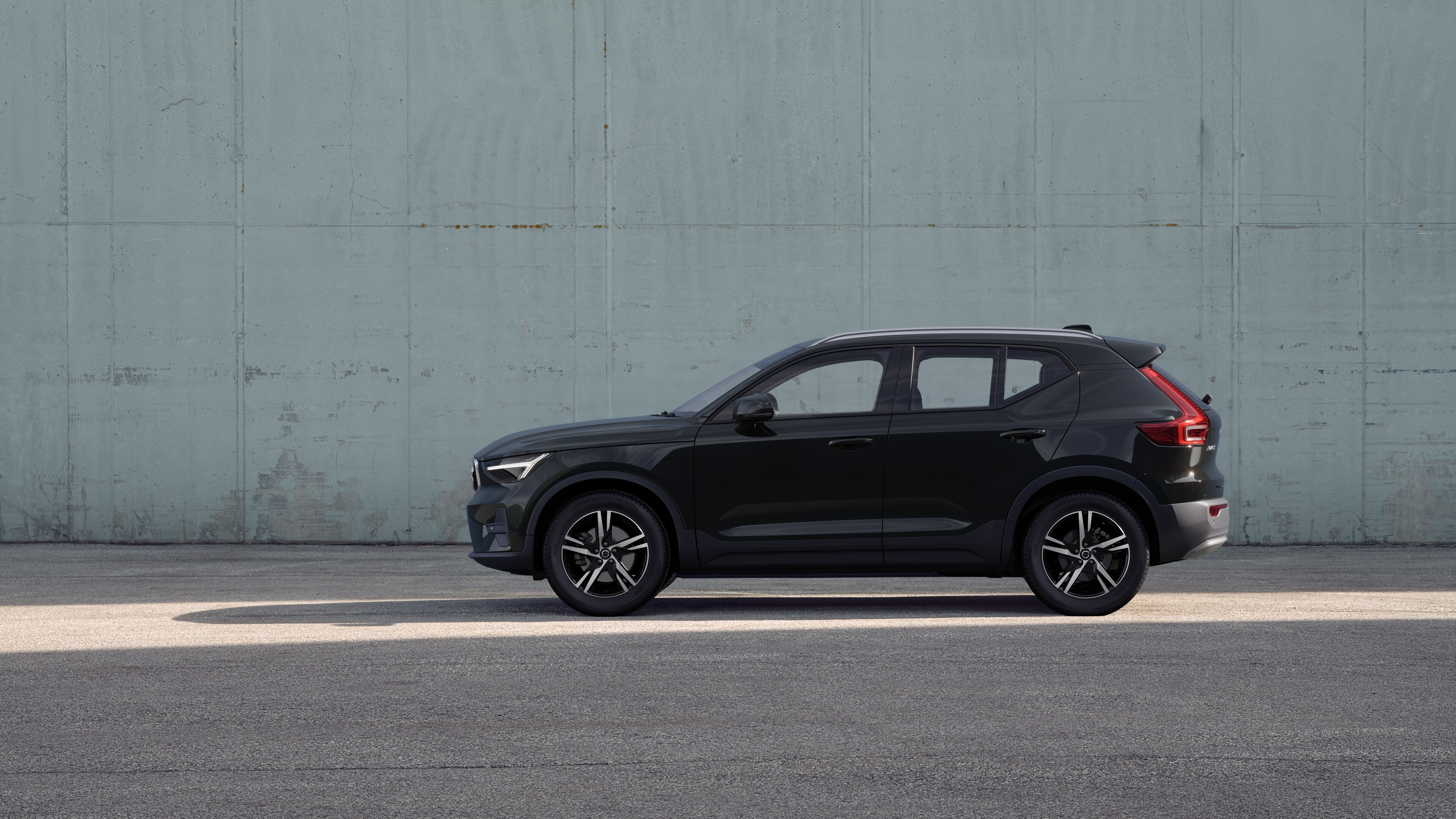 Volvo car, side view, parked against a plain concrete wall background.