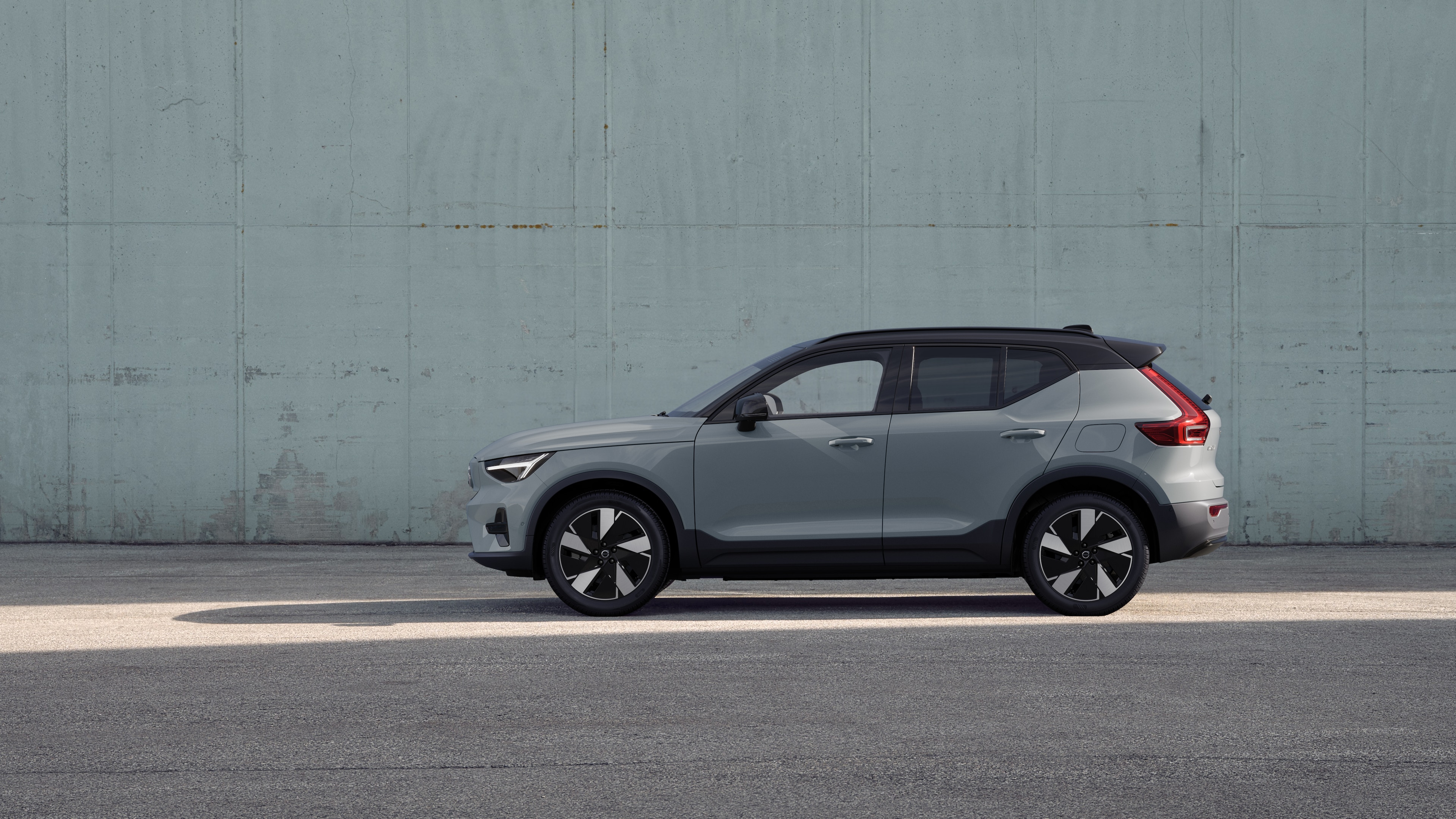 Volvo, zijaanzicht, geparkeerd tegen een effen betonnen muurachtergrond.