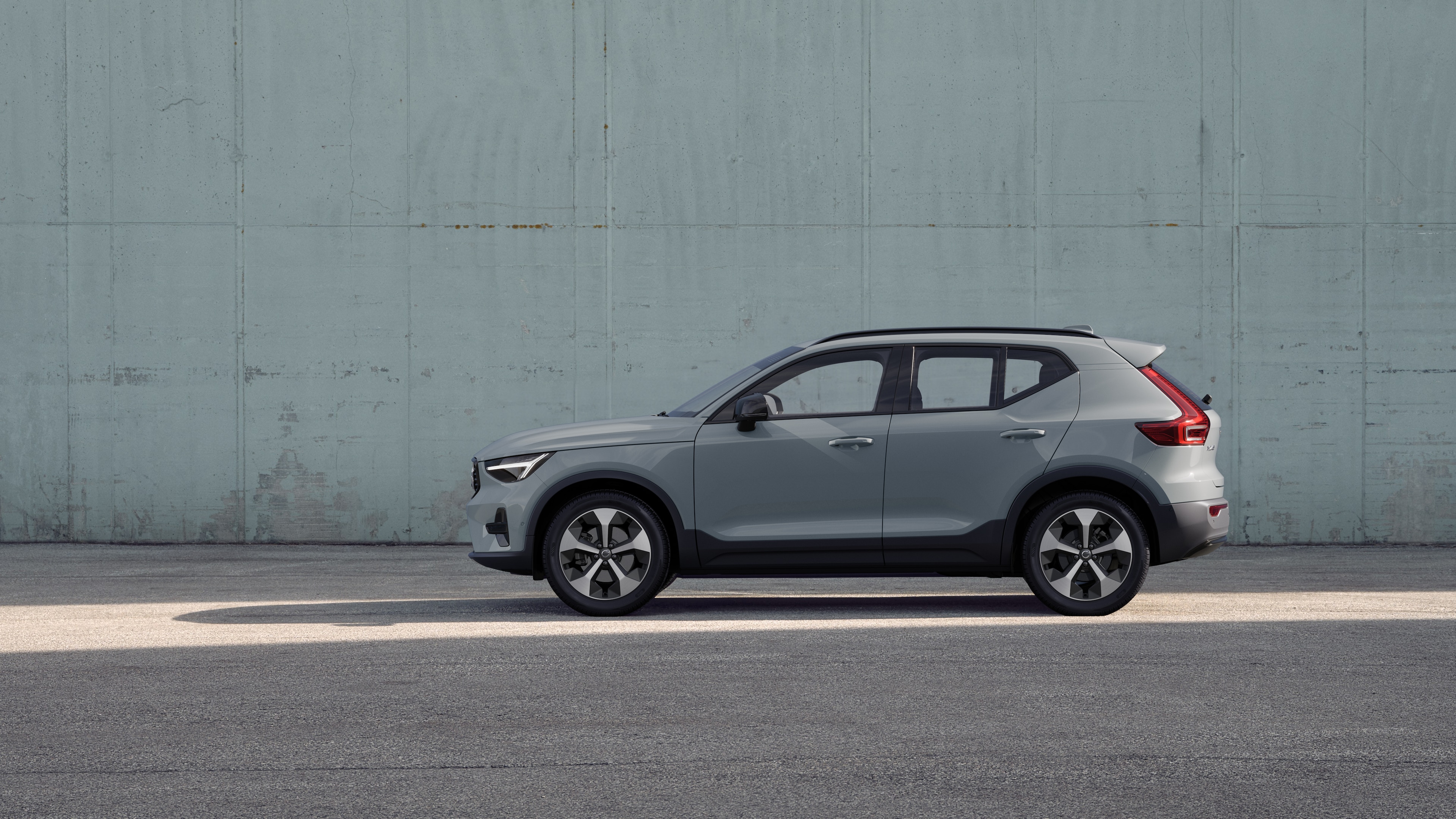 Un'auto Volvo, vista laterale, parcheggiata sullo sfondo di un muro di cemento.