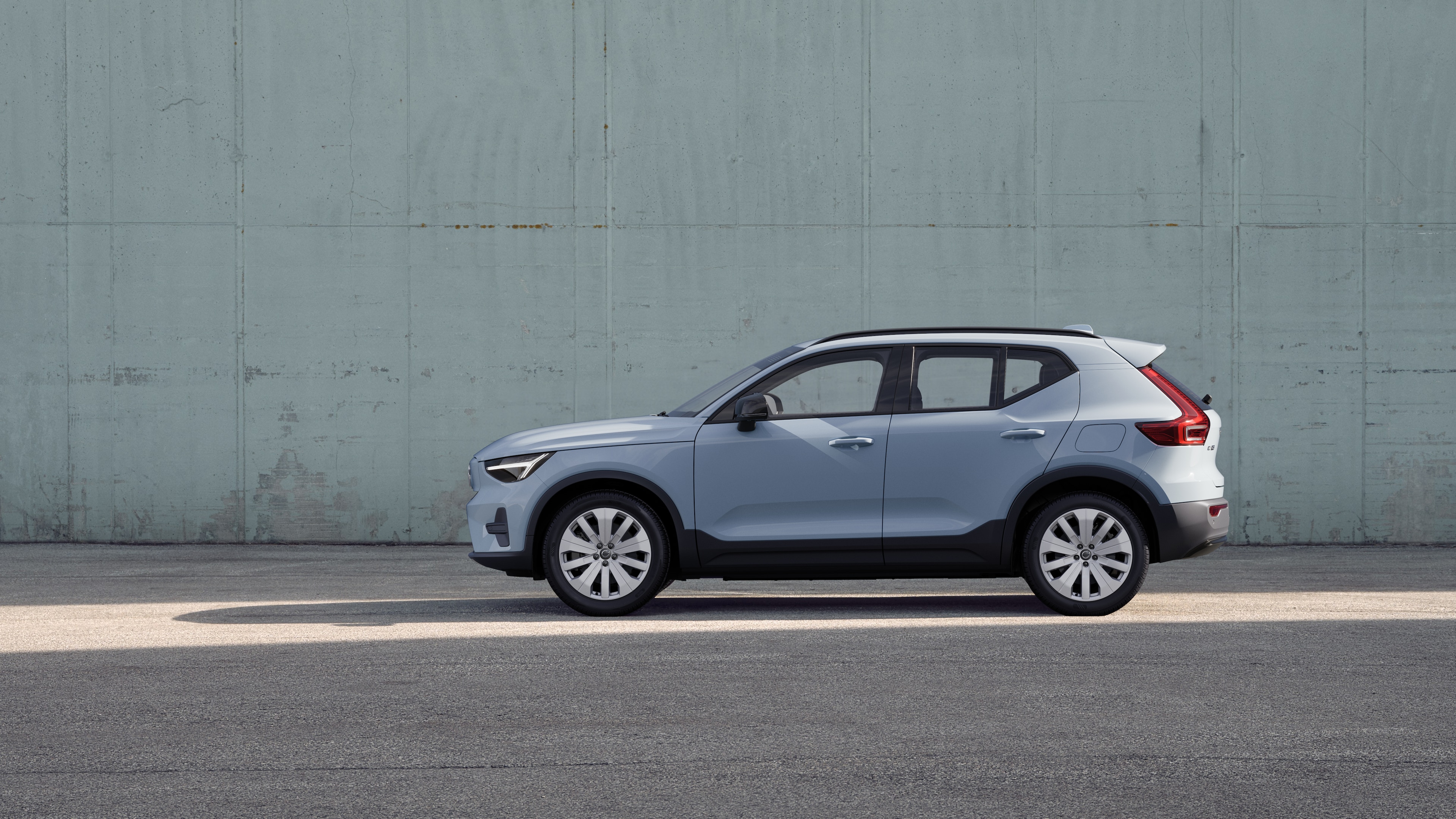 Volvo car, side view, parked against a plain concrete wall background.