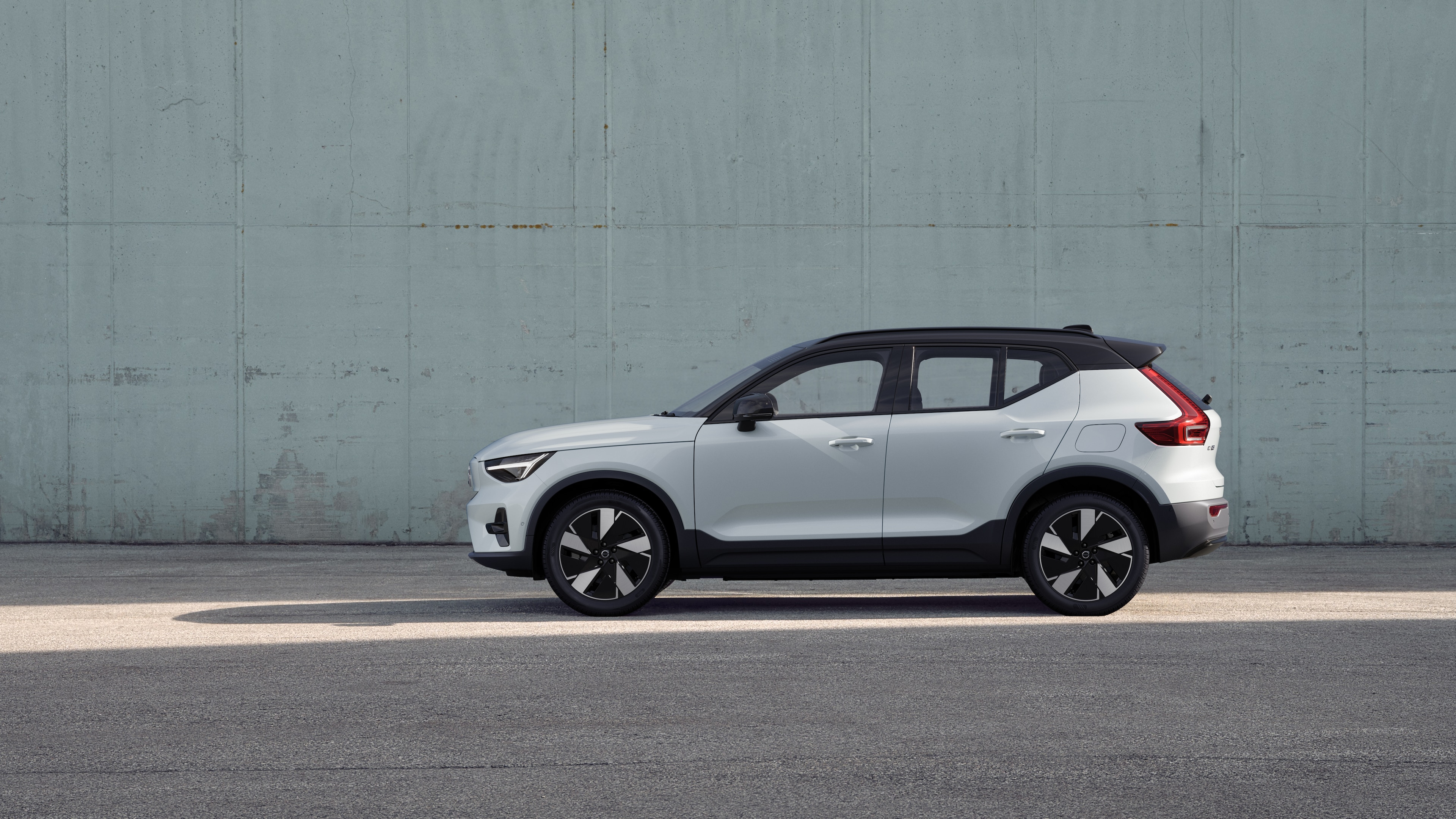 Volvo car, side view, parked against a plain concrete wall background.