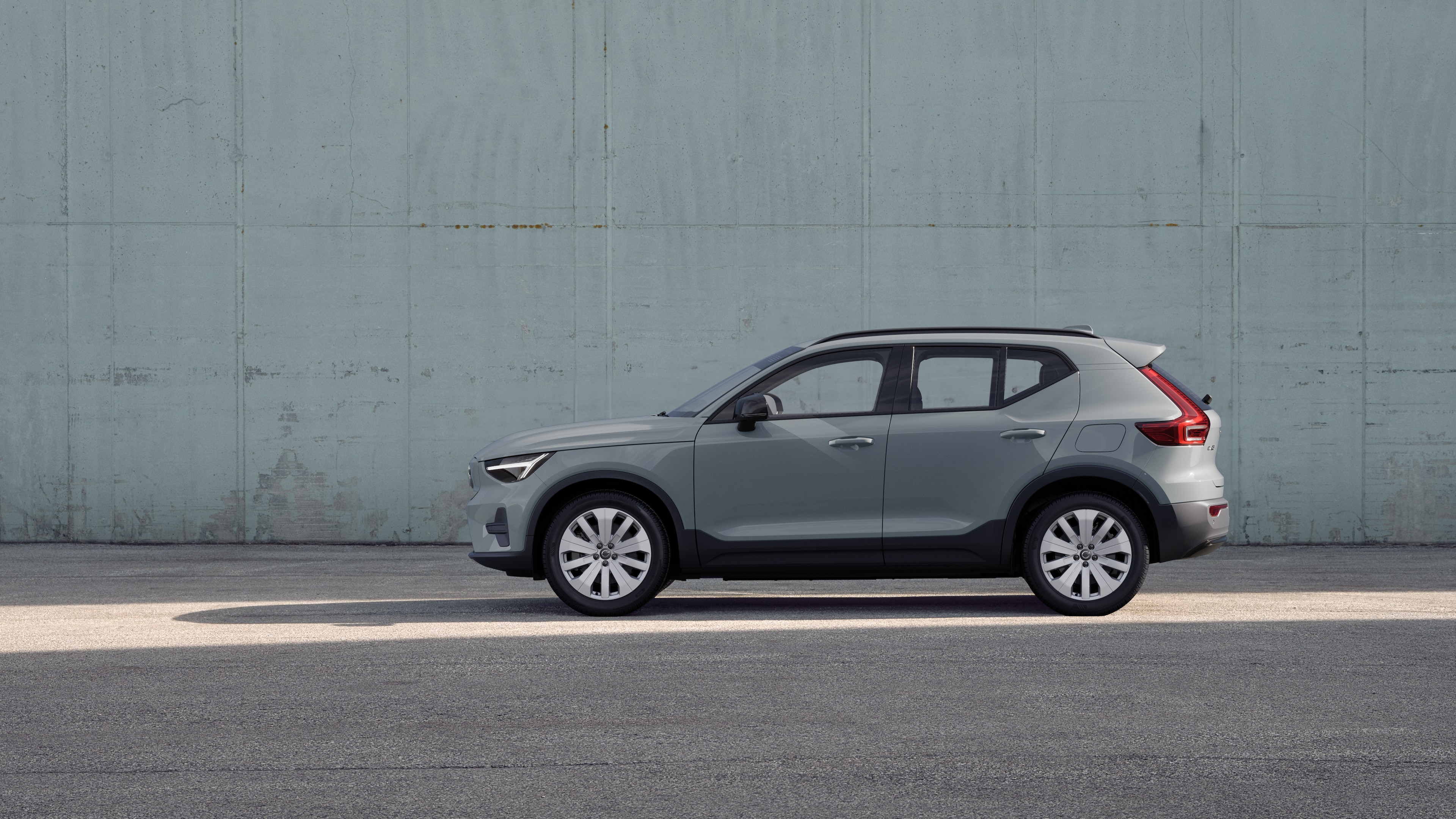 Volvo, zijaanzicht, geparkeerd tegen een effen betonnen muurachtergrond.