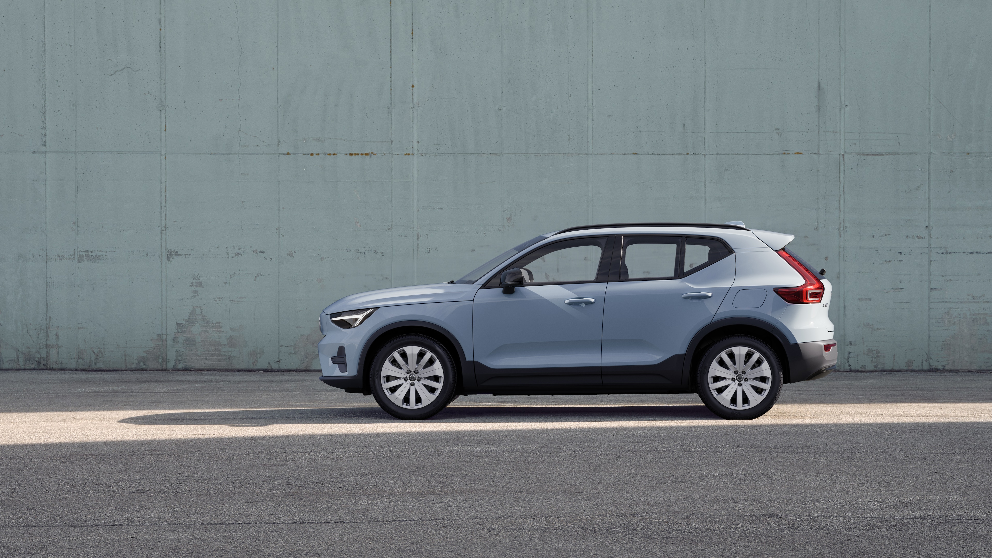 Volvo-auto, zijaanzicht, geparkeerd tegen een effen betonnen muurachtergrond.