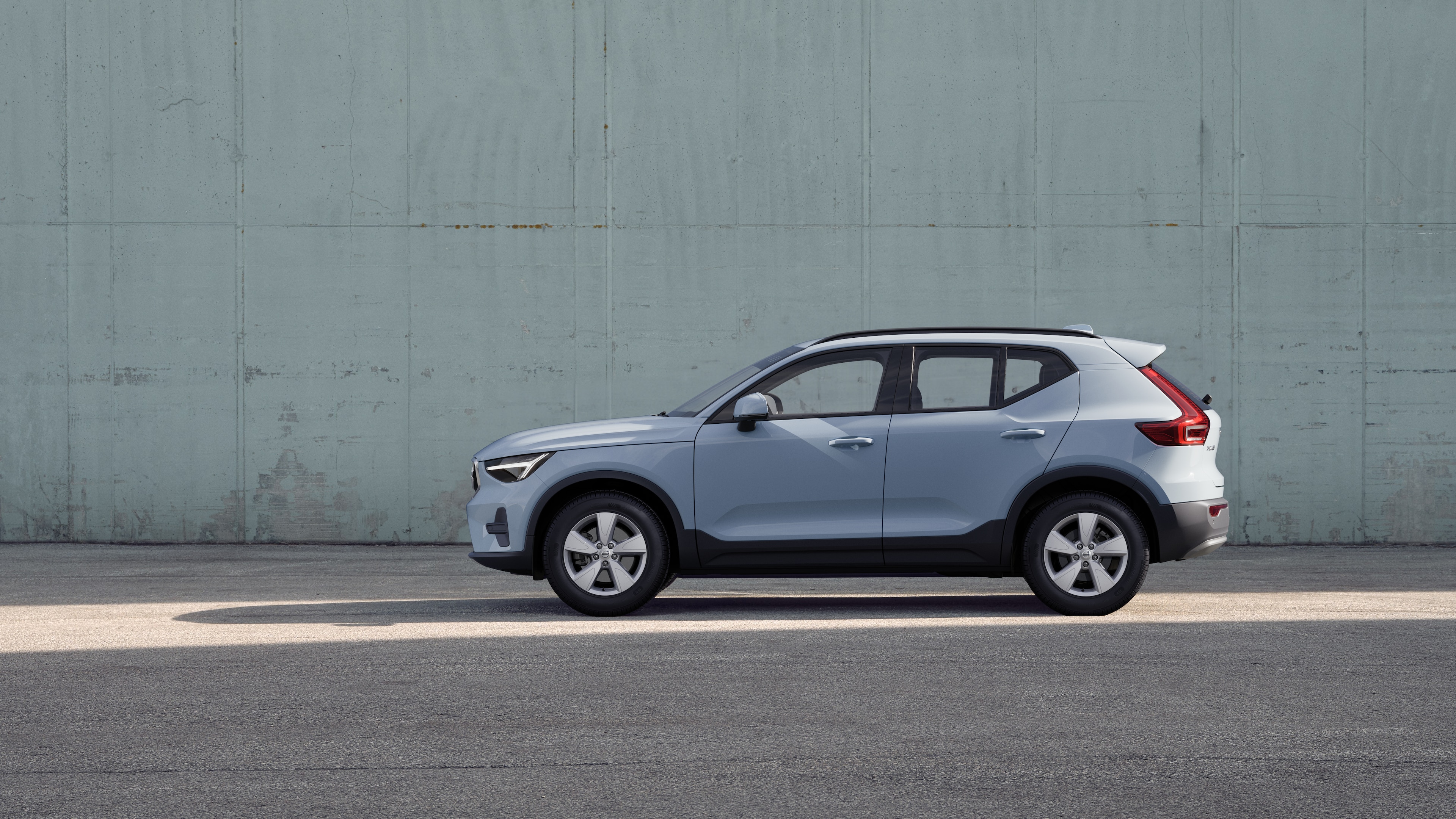 Un'auto Volvo, vista laterale, parcheggiata sullo sfondo di un muro di cemento.