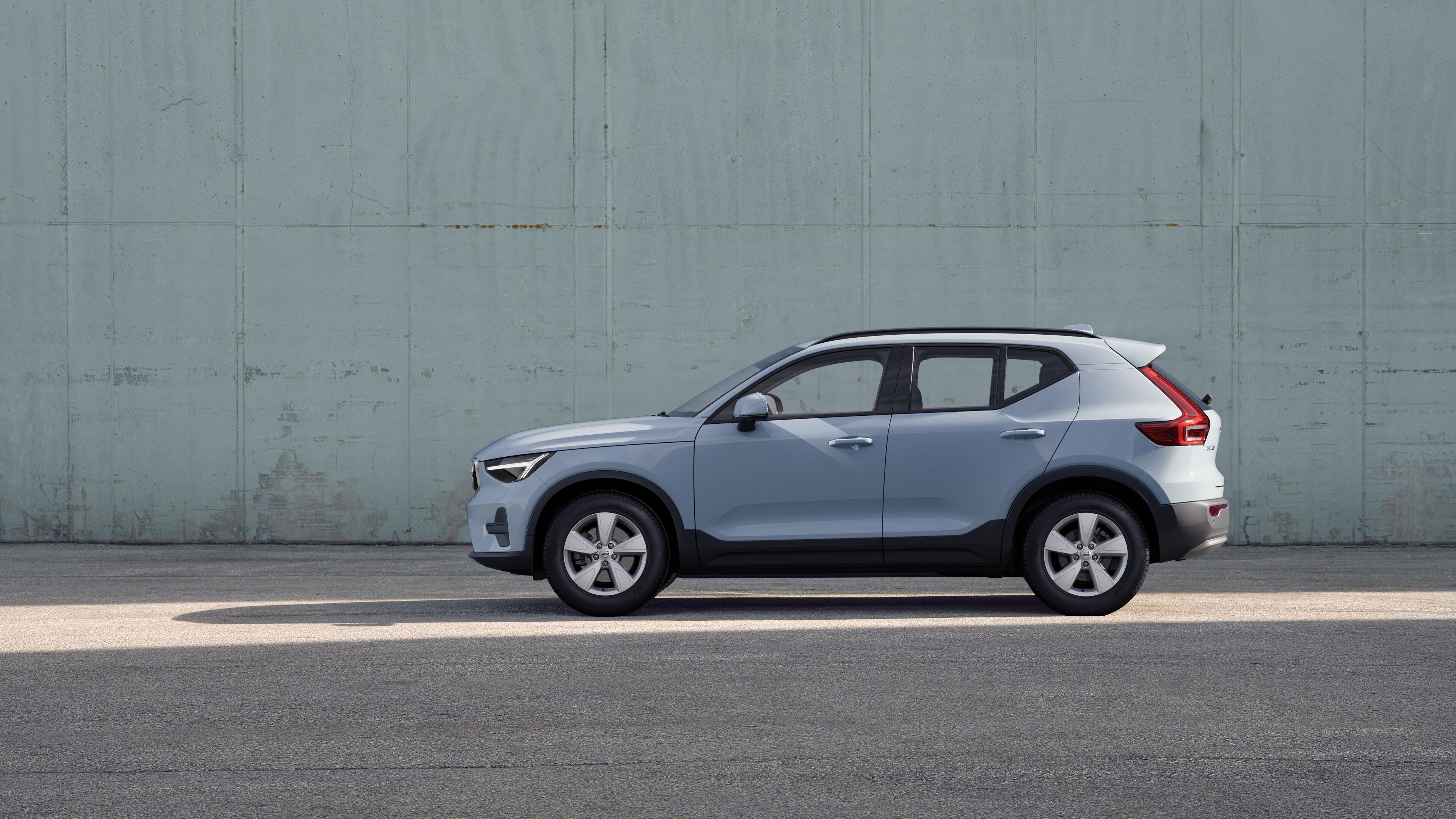Volvo-auto, zijaanzicht, geparkeerd tegen een effen betonnen muurachtergrond.