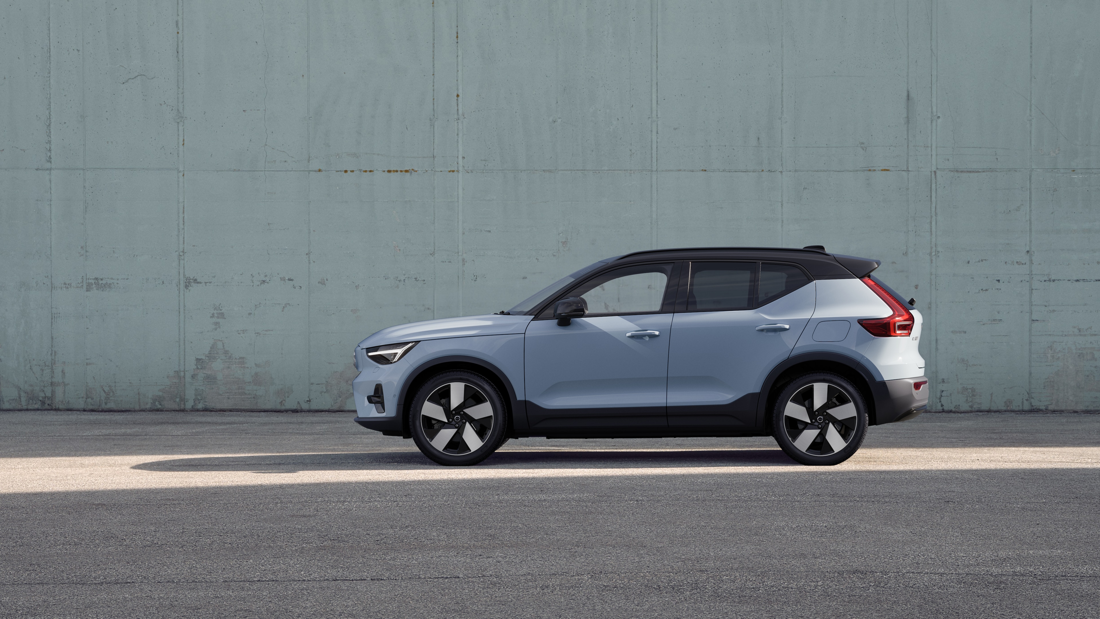 Volvo car, side view, parked against a plain concrete wall background.