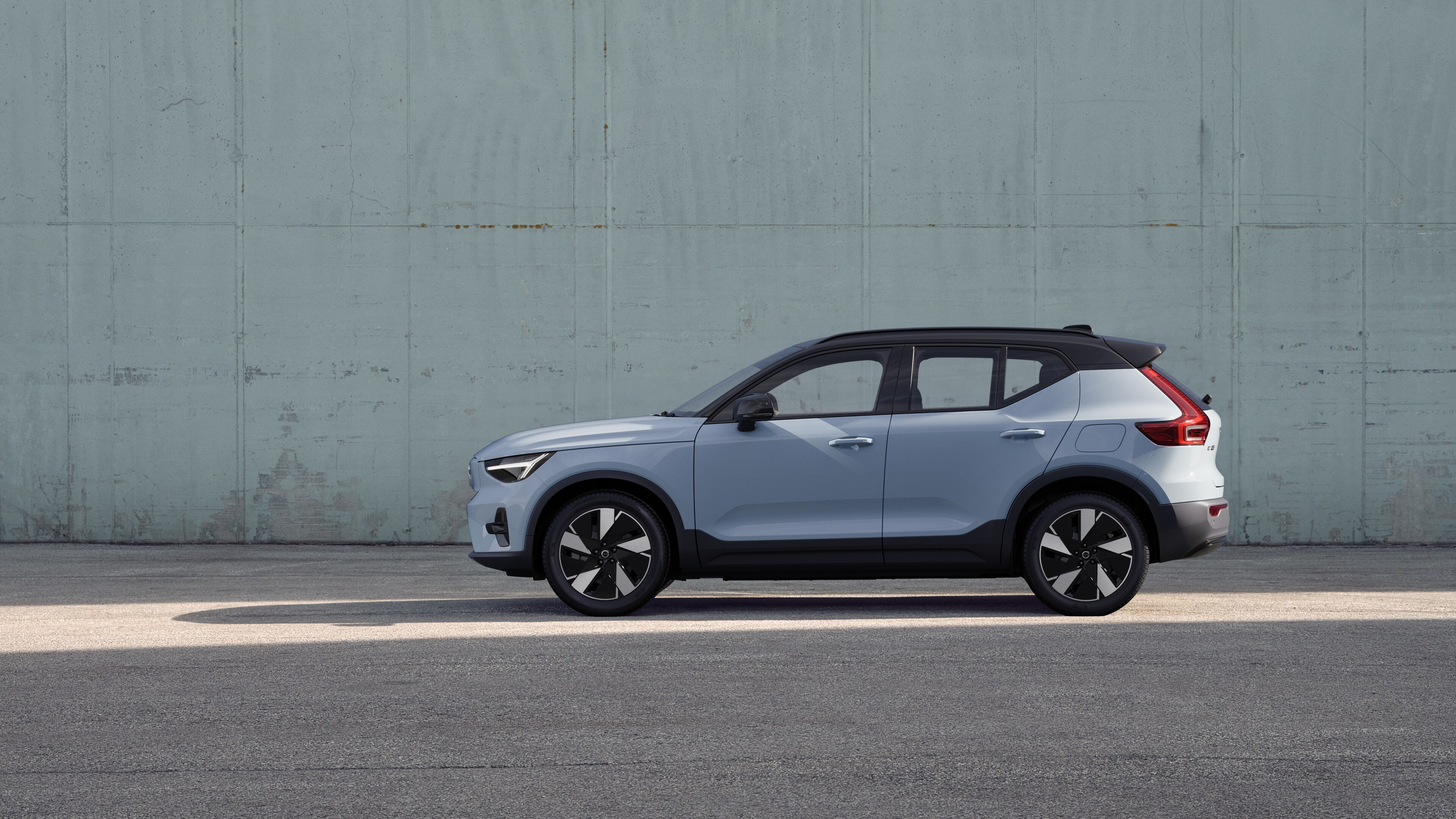 Volvo car, side view, parked against a plain concrete wall background.