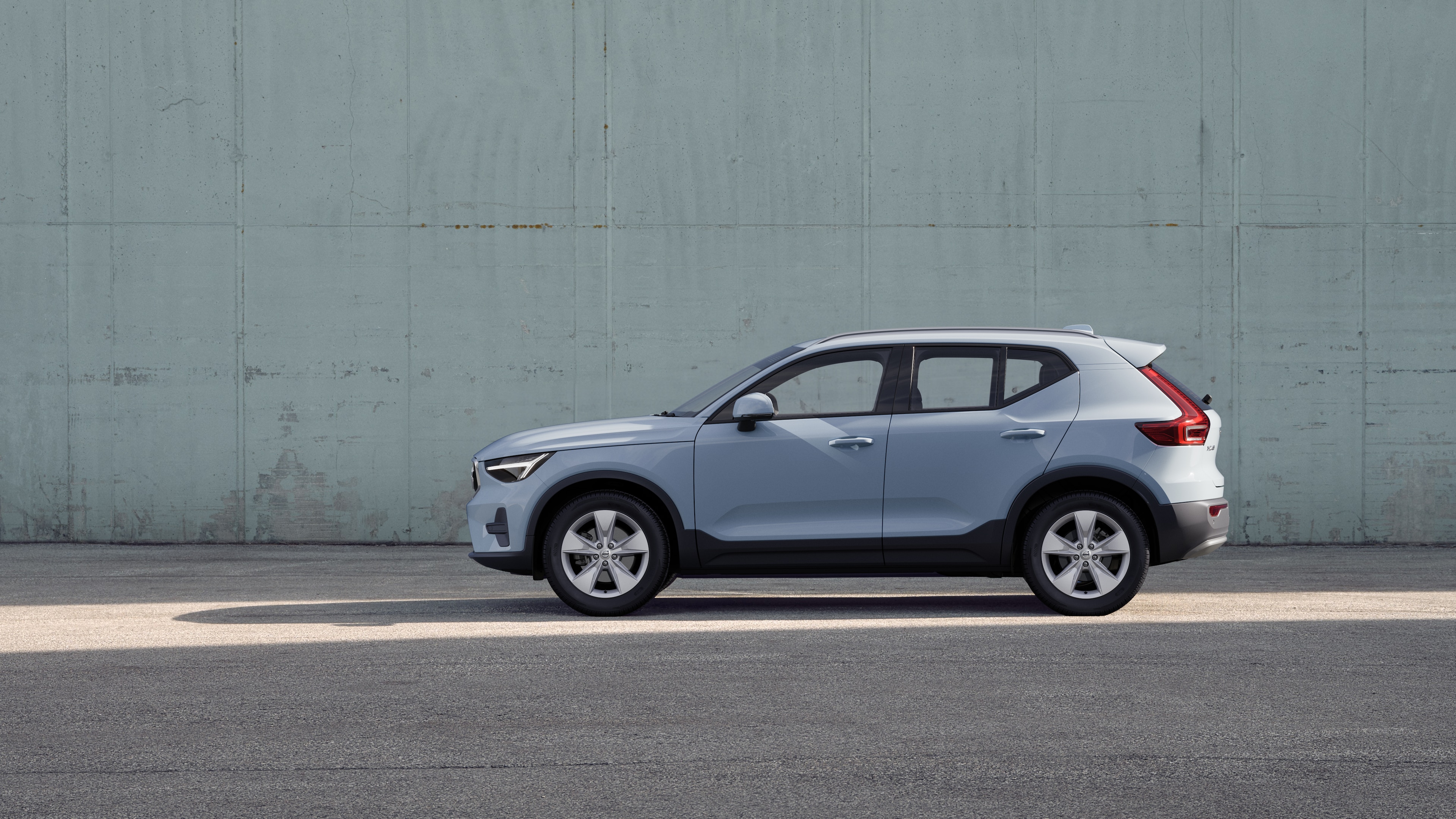 Volvo car, side view, parked against a plain concrete wall background.