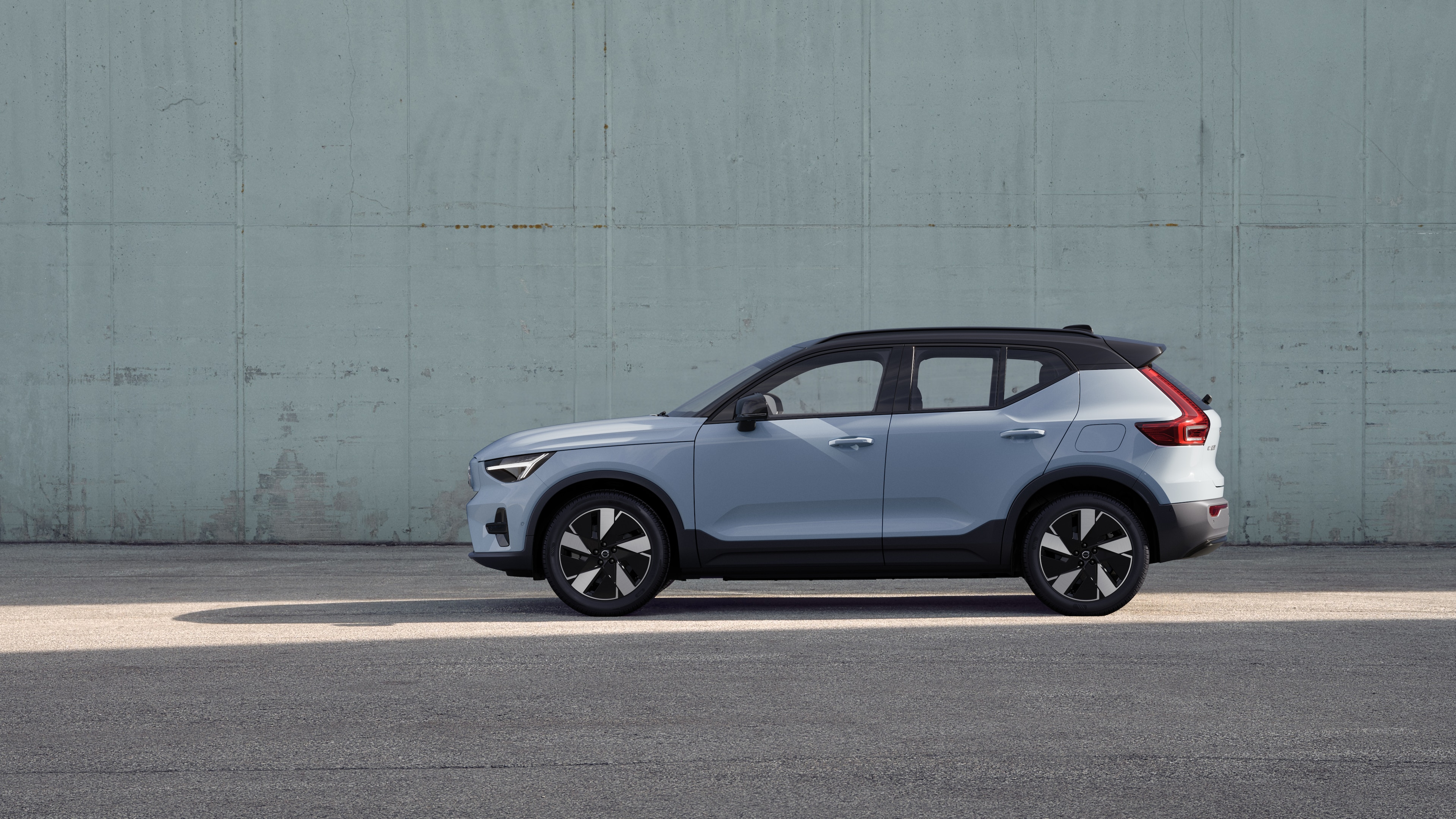 Düz beton bir duvar arka planına park edilmiş Volvo otomobilin yandan görünümü.