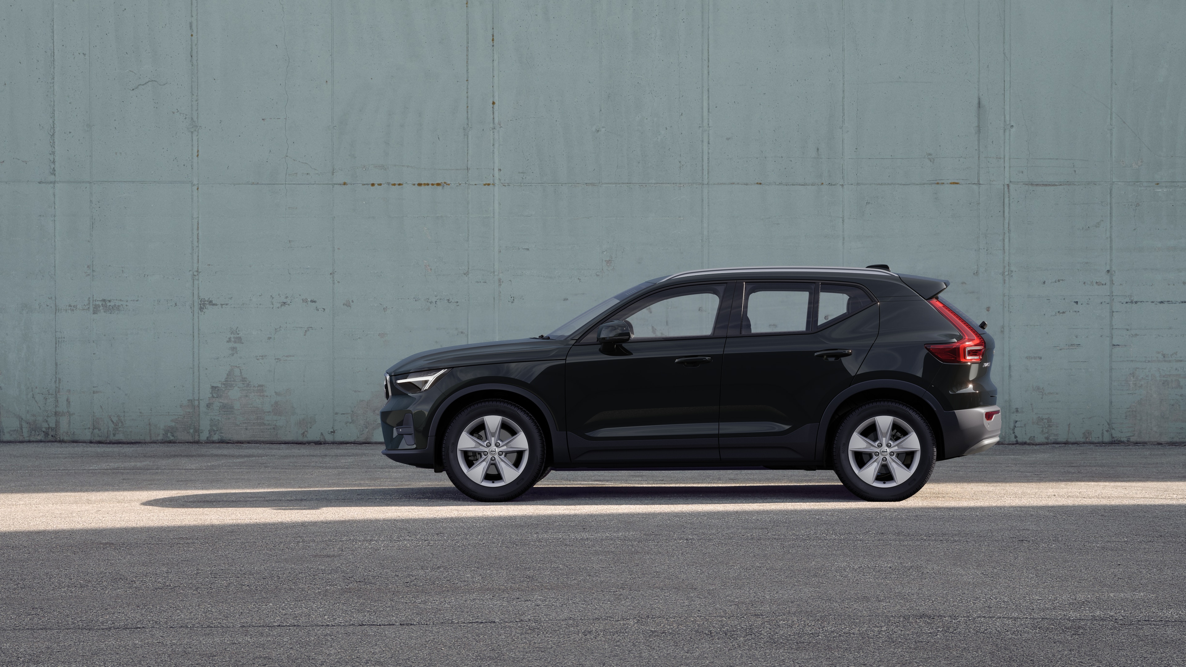 Volvo car, side view, parked against a plain concrete wall background.