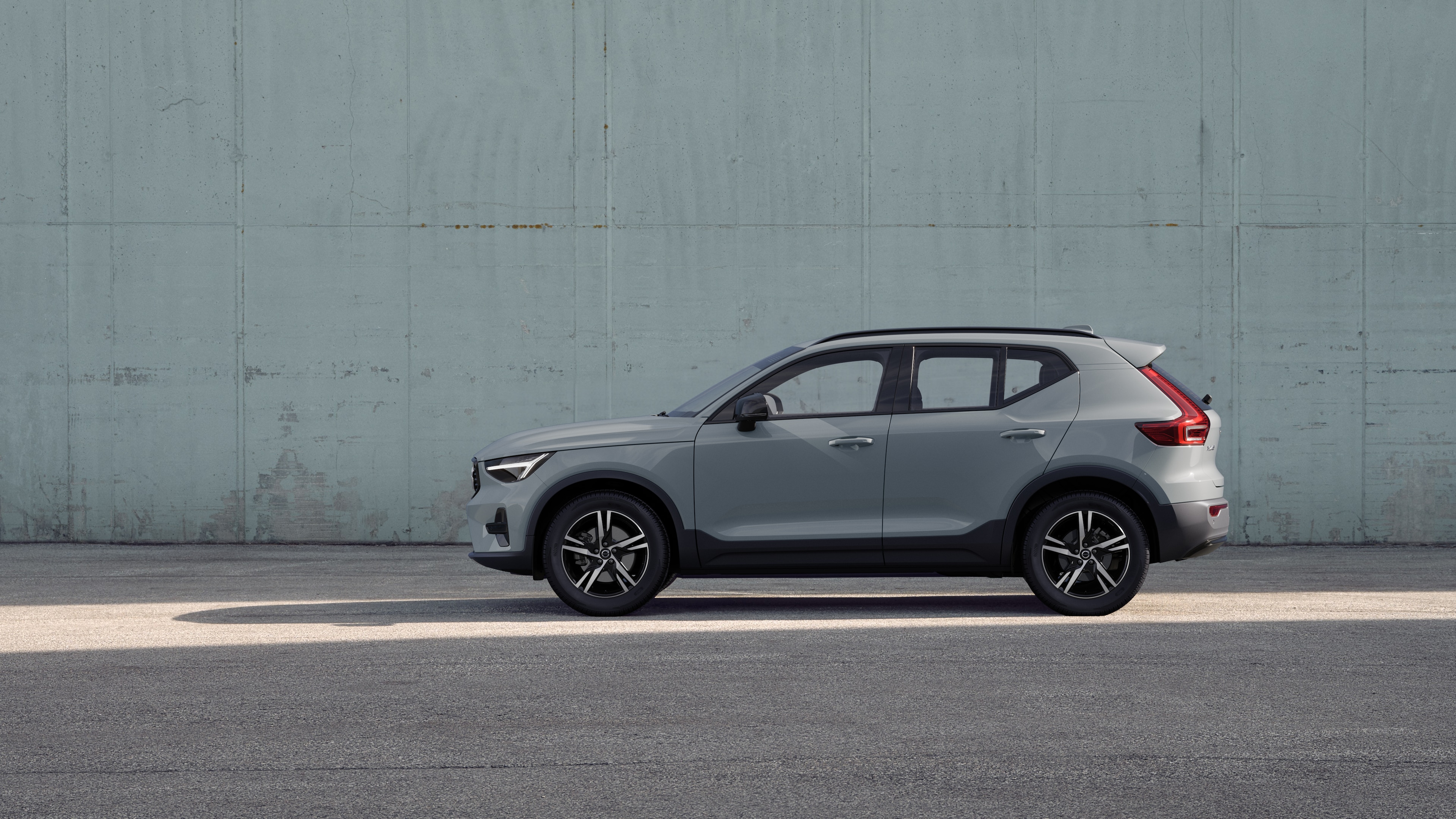 Un'auto Volvo, vista laterale, parcheggiata sullo sfondo di un muro di cemento.
