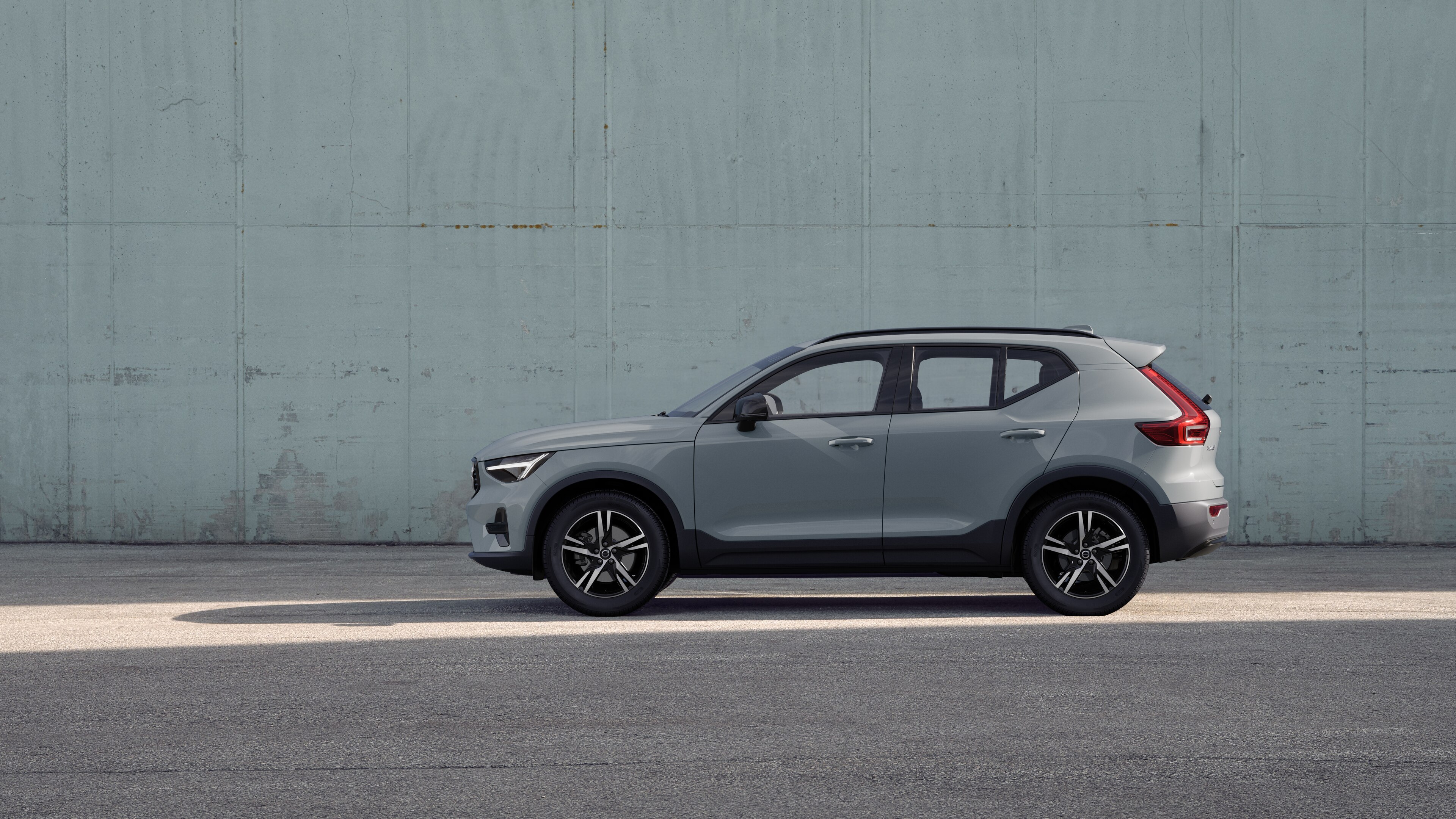 Un'auto Volvo, vista laterale, parcheggiata sullo sfondo di un muro di cemento.