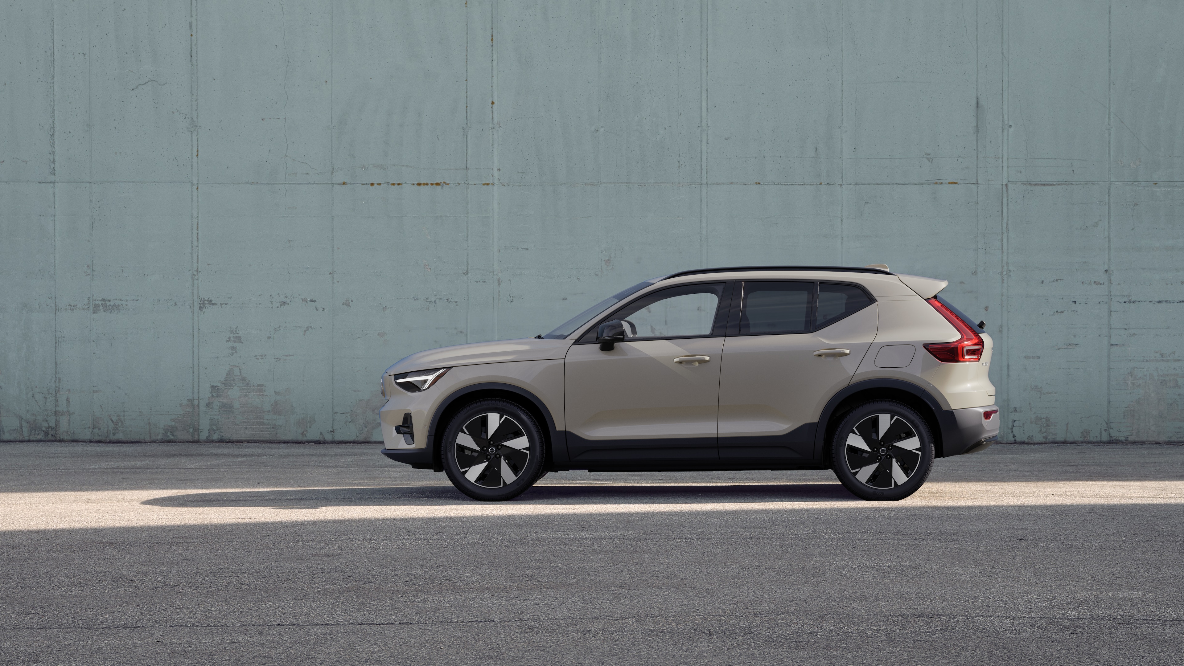 Volvo car, side view, parked against a plain concrete wall background.